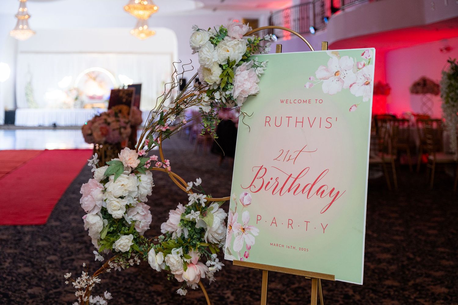Event venue decorated with elegant floral arrangements and mint green signage for a birthday celebration.