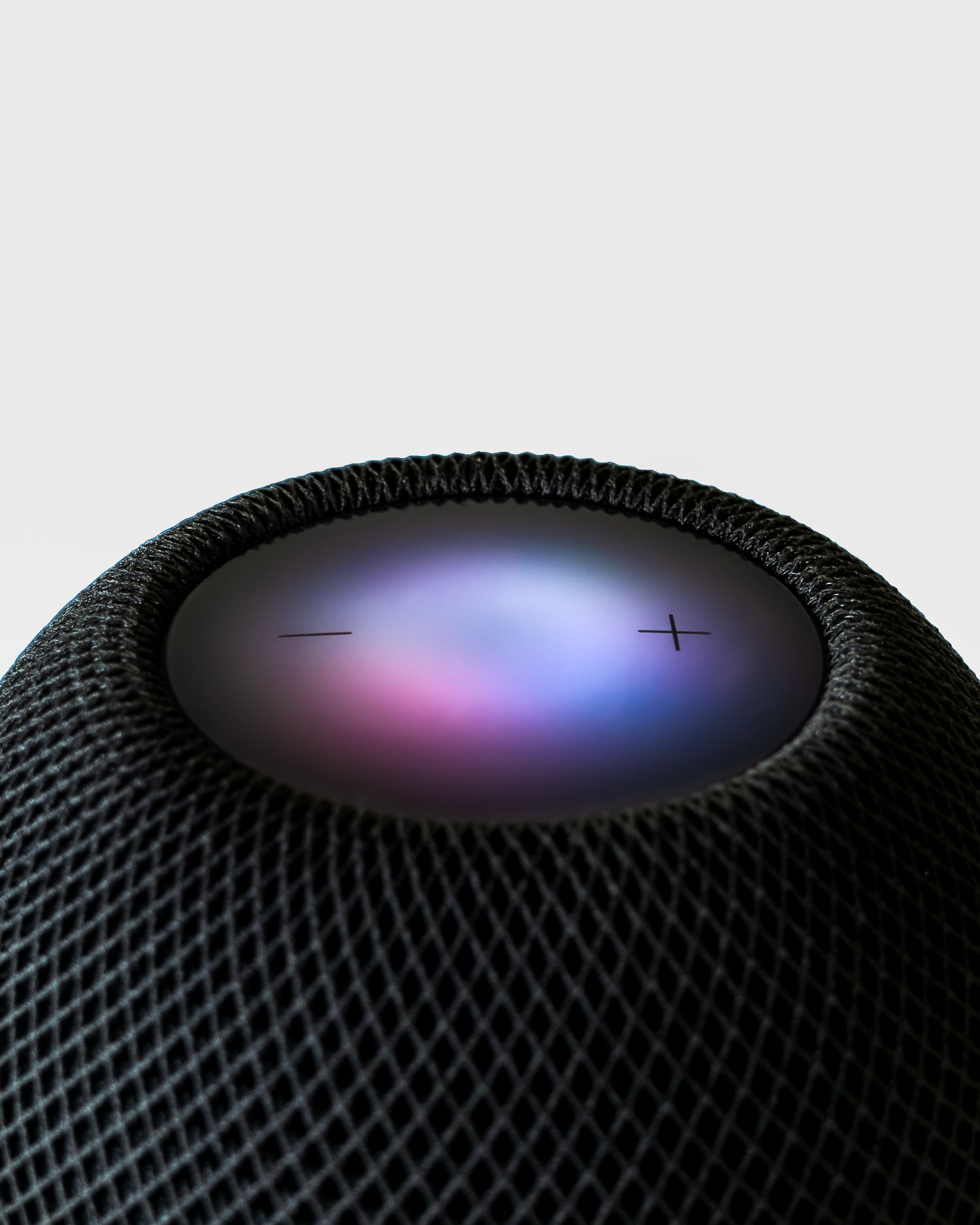 Close-up of HomePod Mini's illuminated touch surface displaying colorful light patterns.