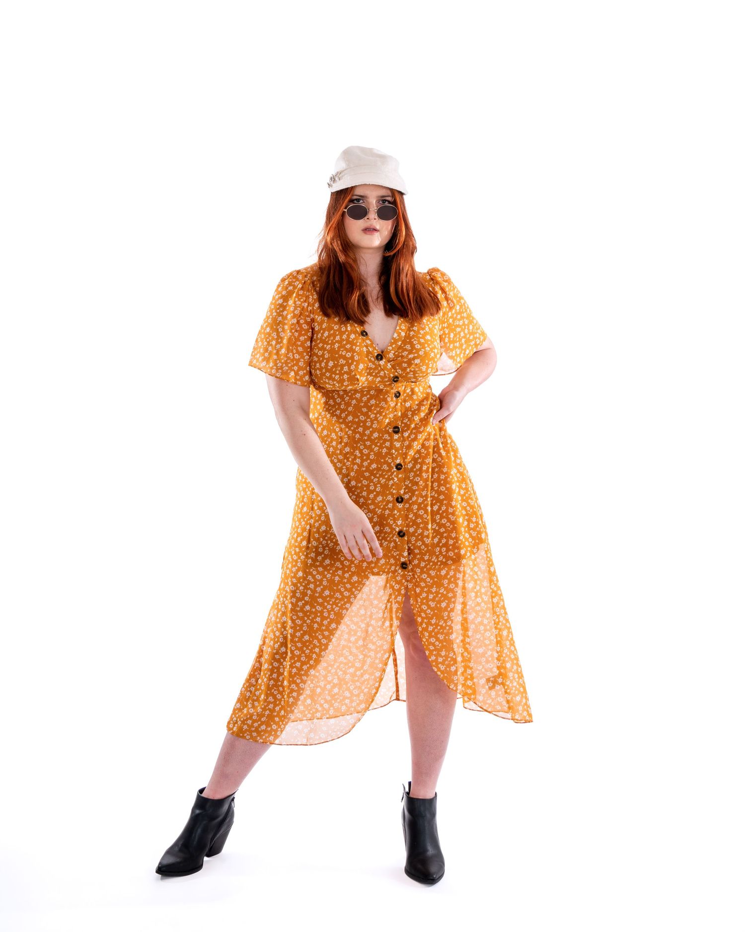 A model poses in a flowing yellow polka dot dress and boots against a white background.