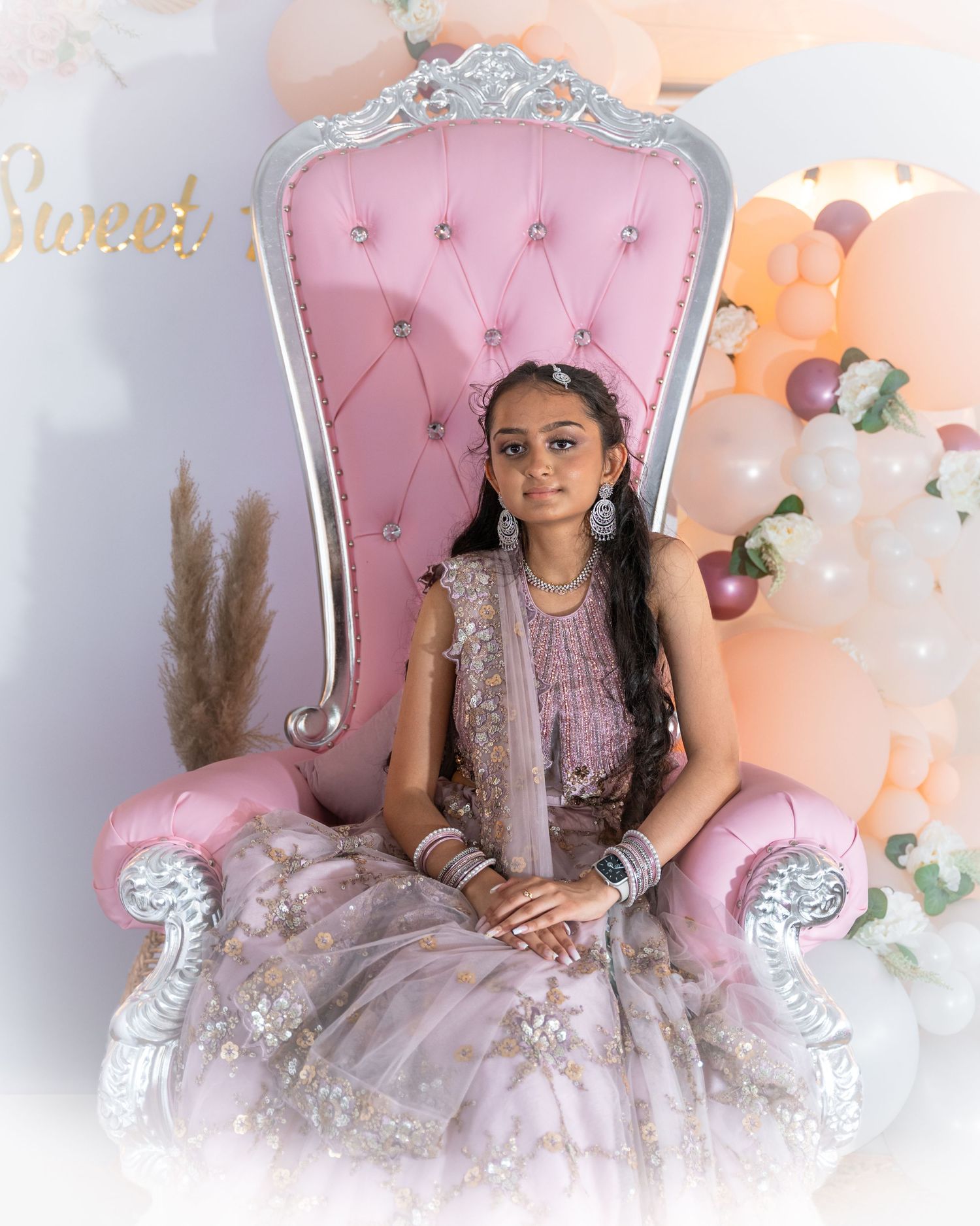Decorative birthday celebration setup with pink throne chair and sparkly accents.