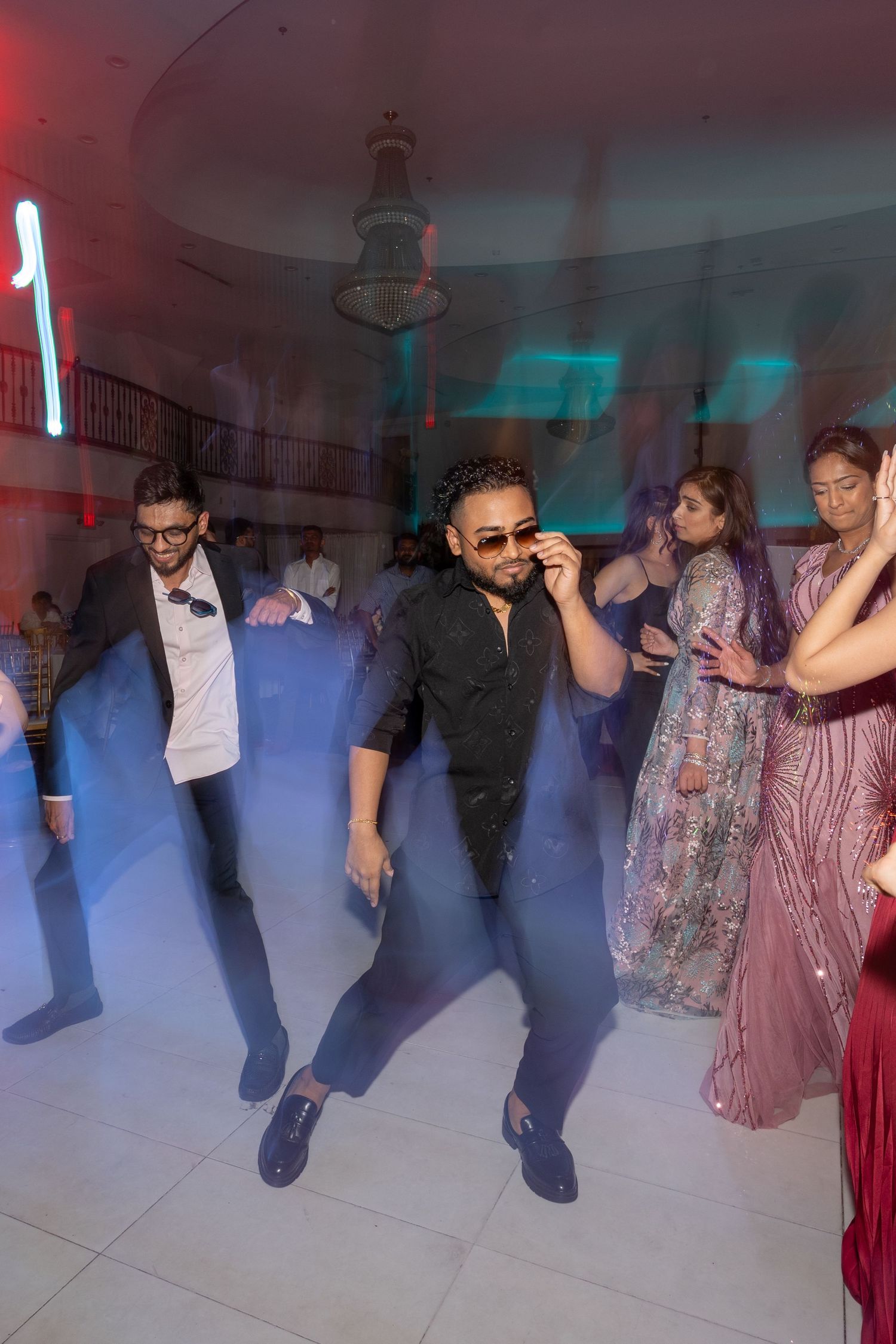 Wedding reception dance floor with colorful lighting and guests dancing in a joyful atmosphere.