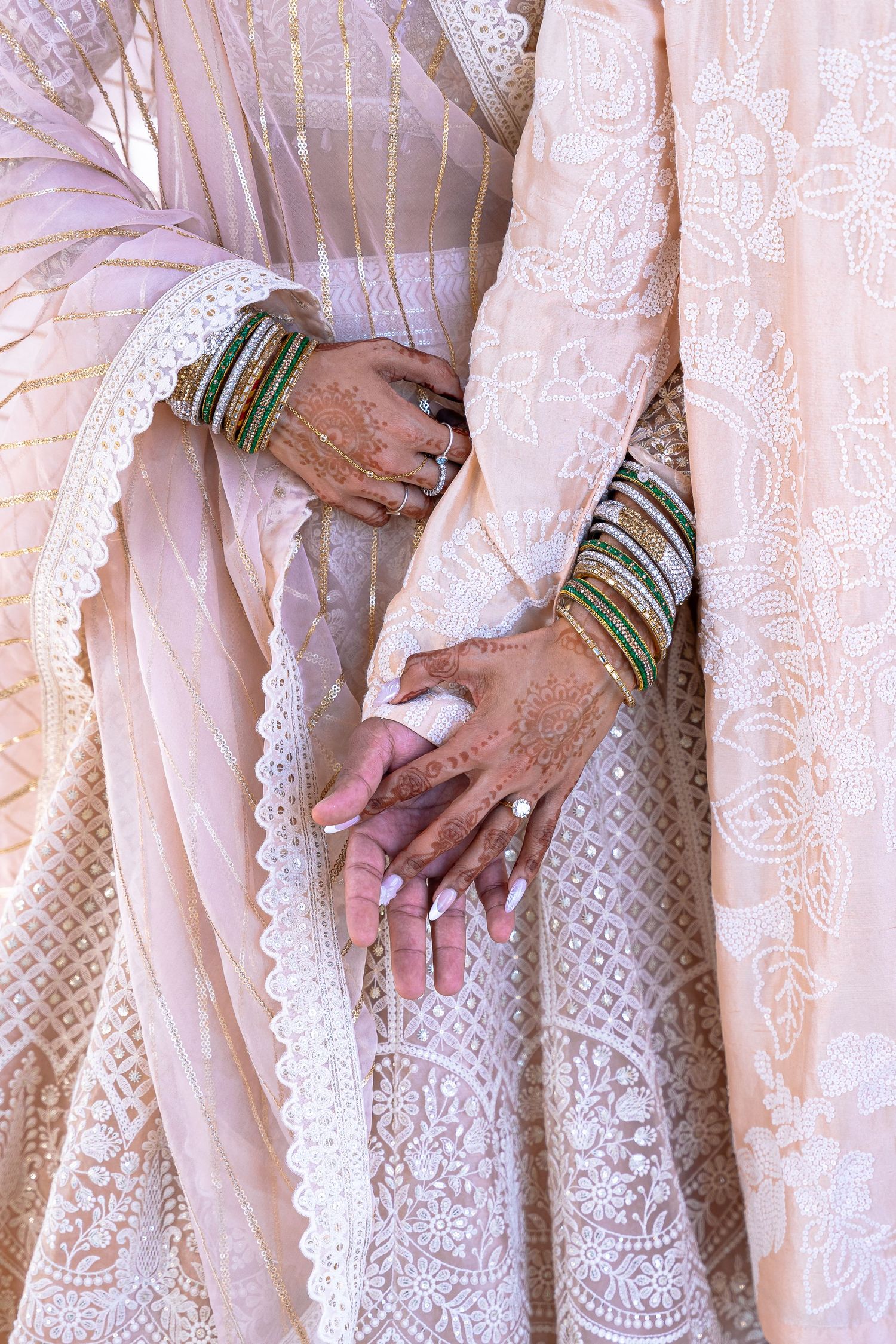 Close-up details of intricate lace wedding dress with traditional bangles and jewelry.