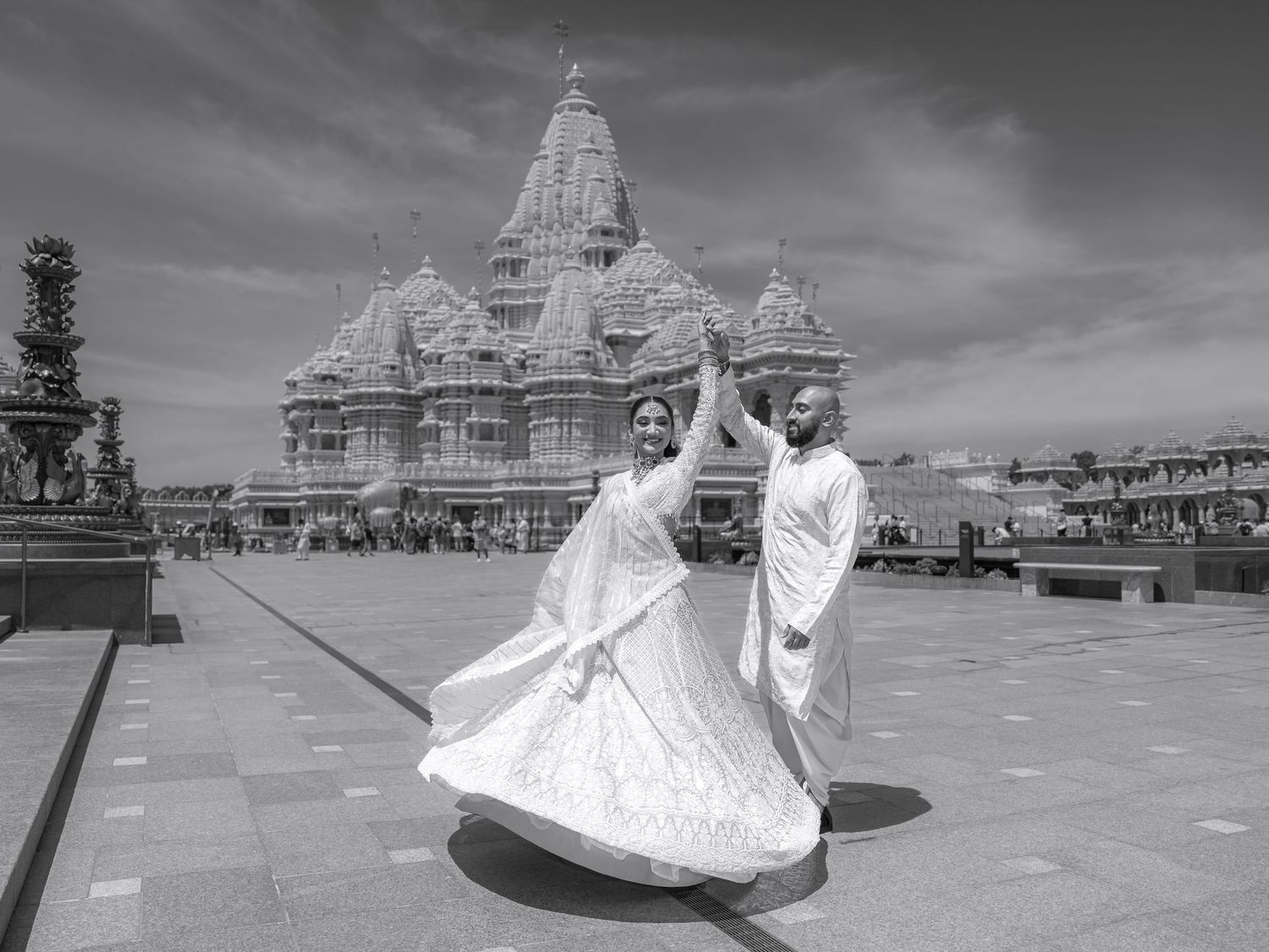 Black and white photos of couple dancing joyfully at ornate temple location.