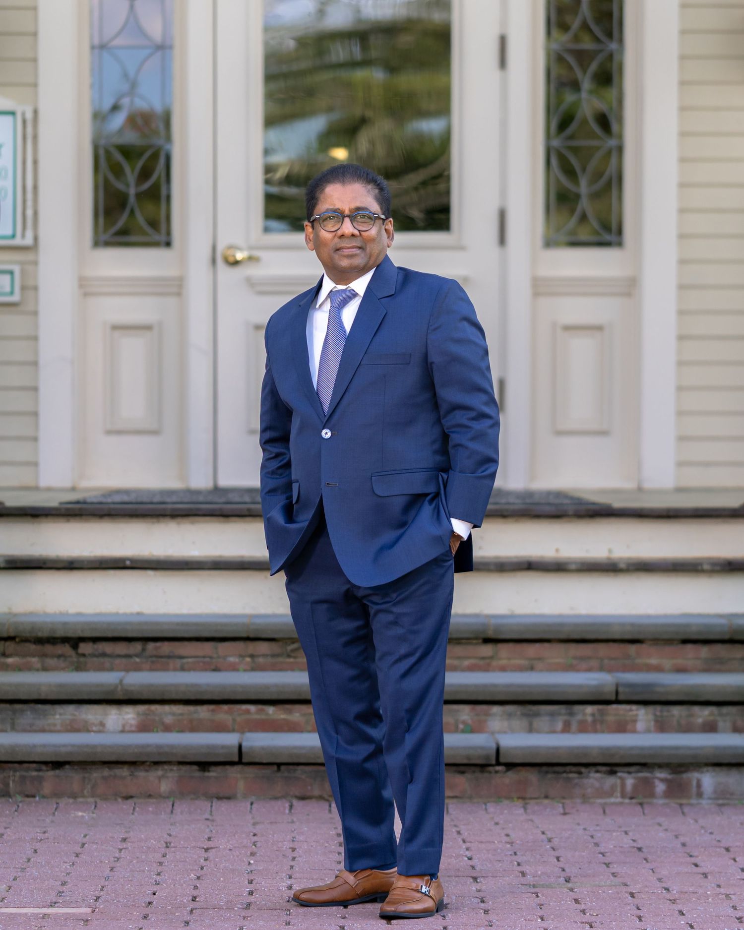 Professional in navy suit standing confidently on building entrance steps.