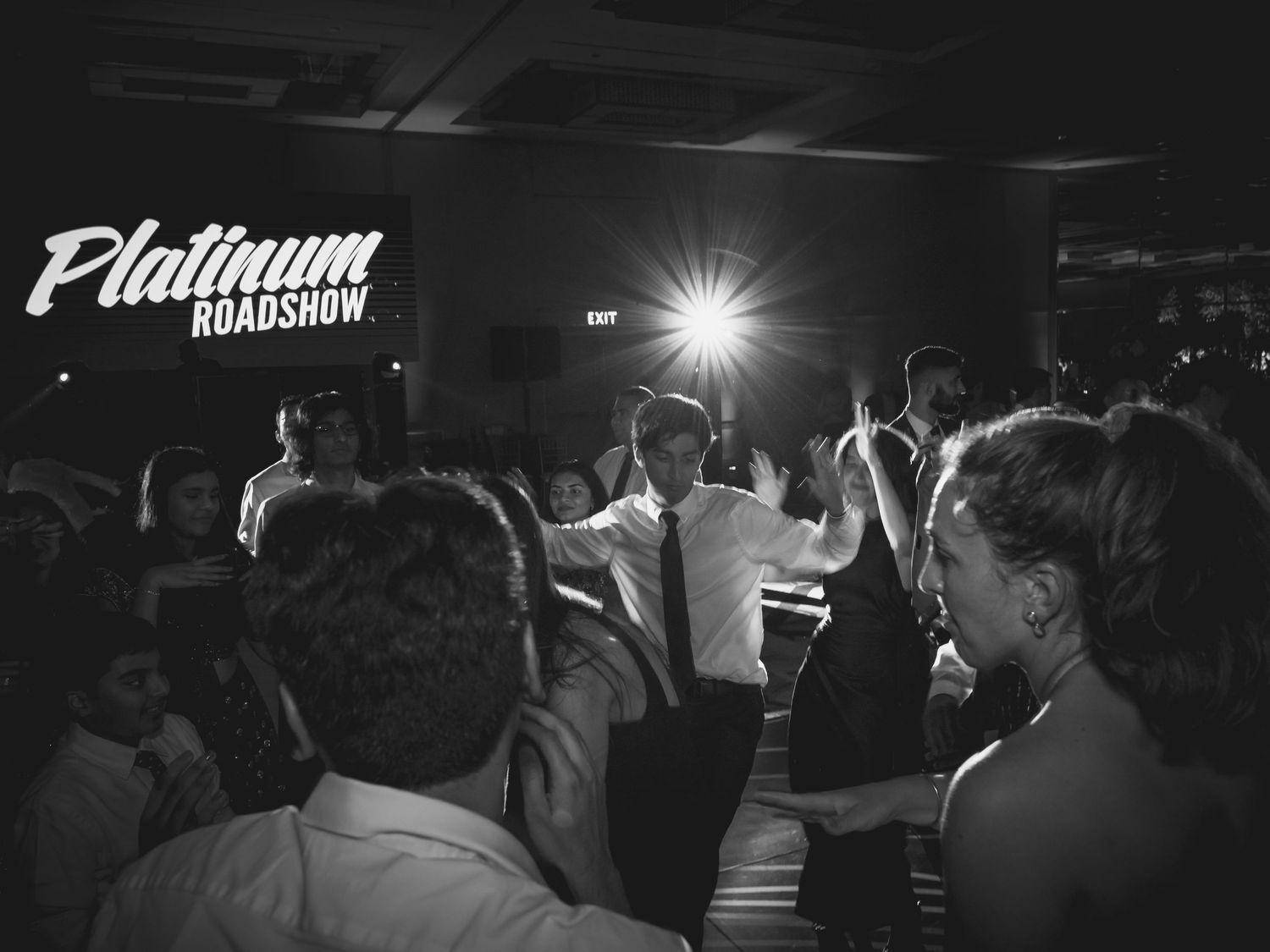 Black and white photo of a crowded nightclub dance floor with overhead lighting.