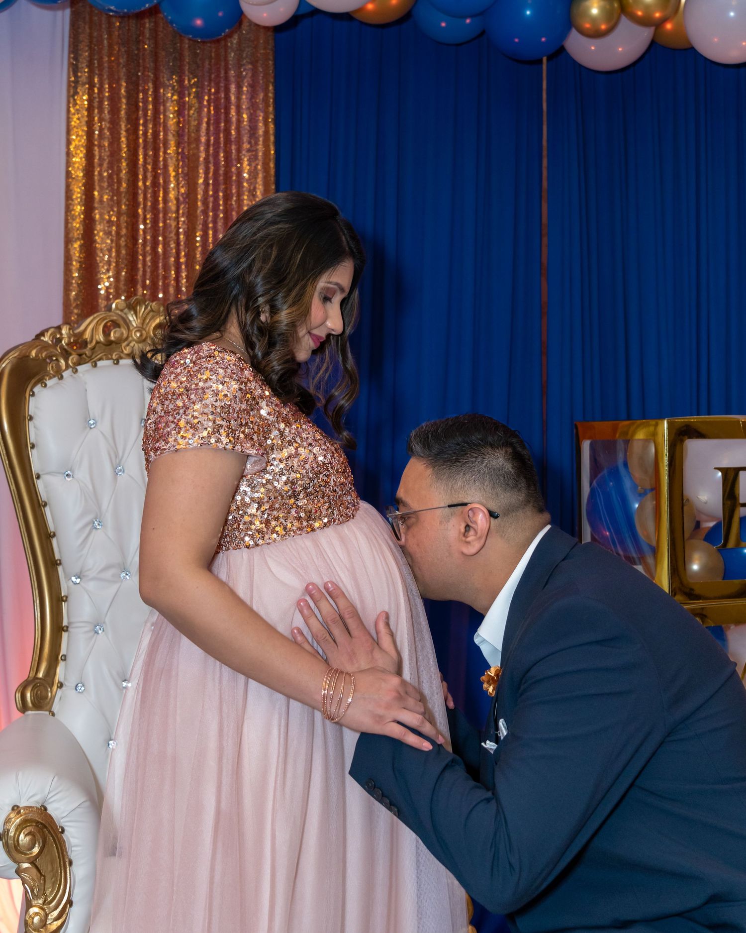 Baby shower celebration with elegant balloon decor and golden curtain backdrop.