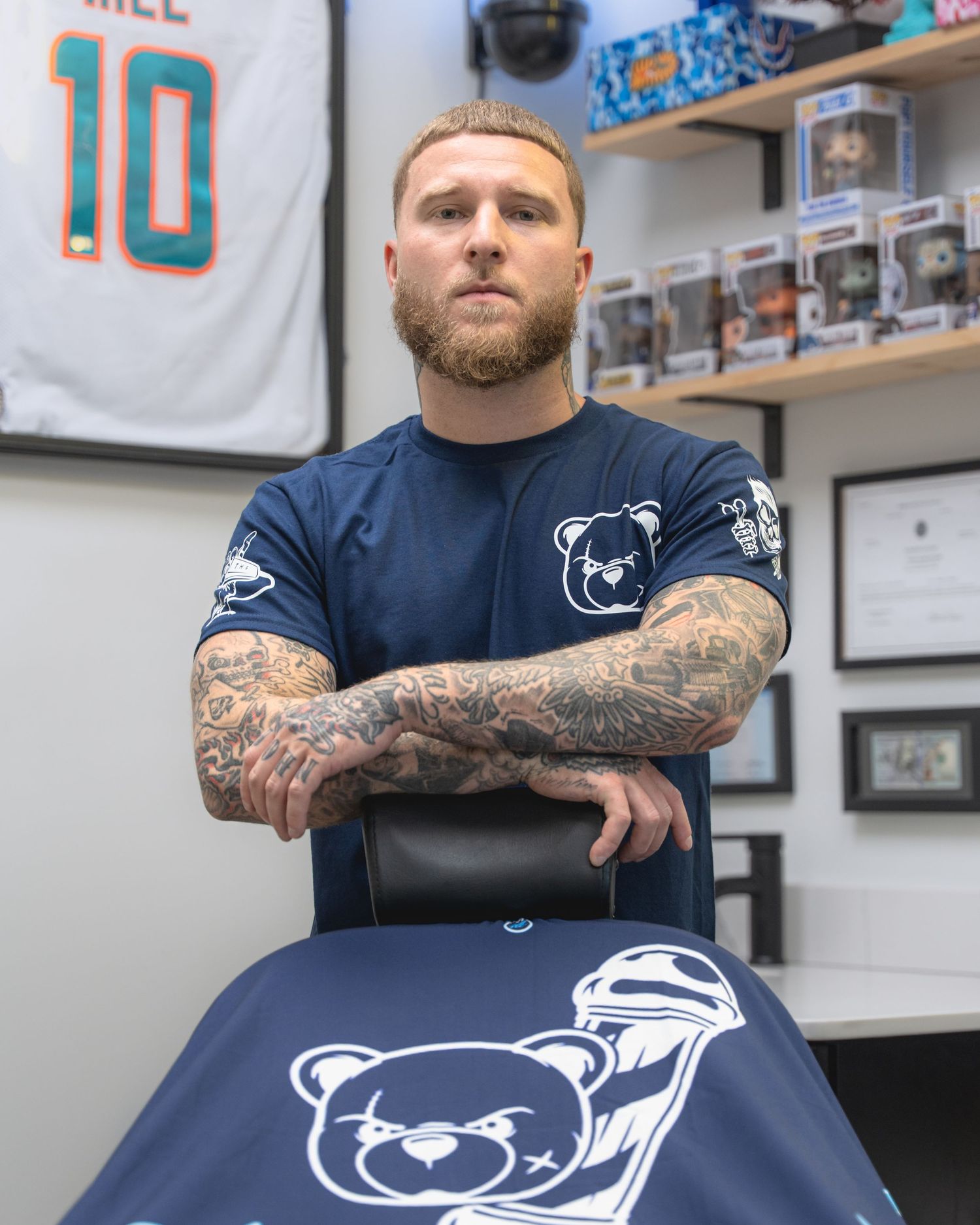 A barber shop interior with sports memorabilia and a navy blue chair displaying a bear logo design.