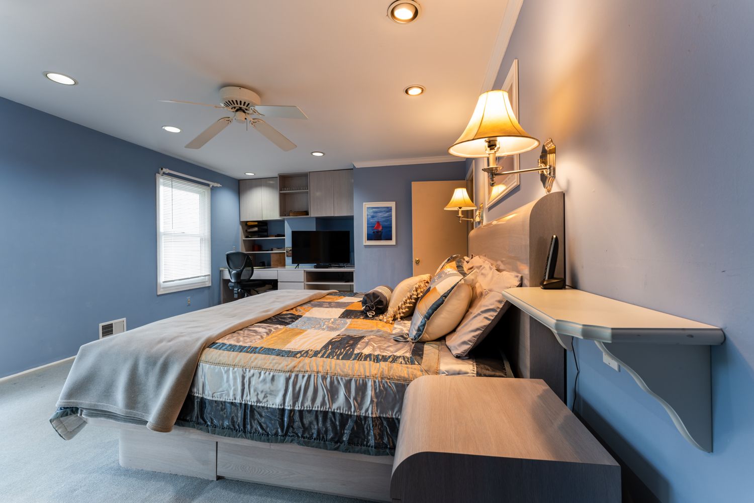 A modern studio apartment interior featuring white cabinetry, gray walls, and recessed lighting creates a sleek living space.