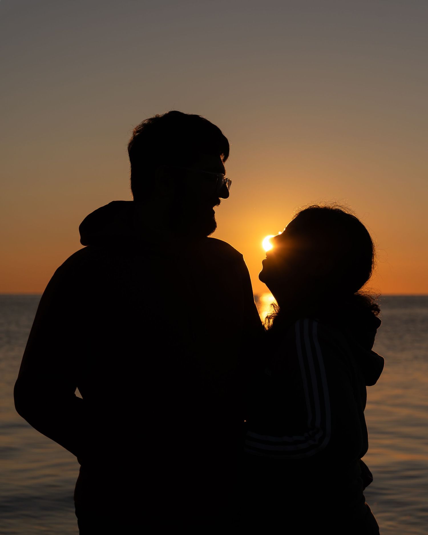 Dark silhouettes against a golden sunset sky over calm ocean waters.