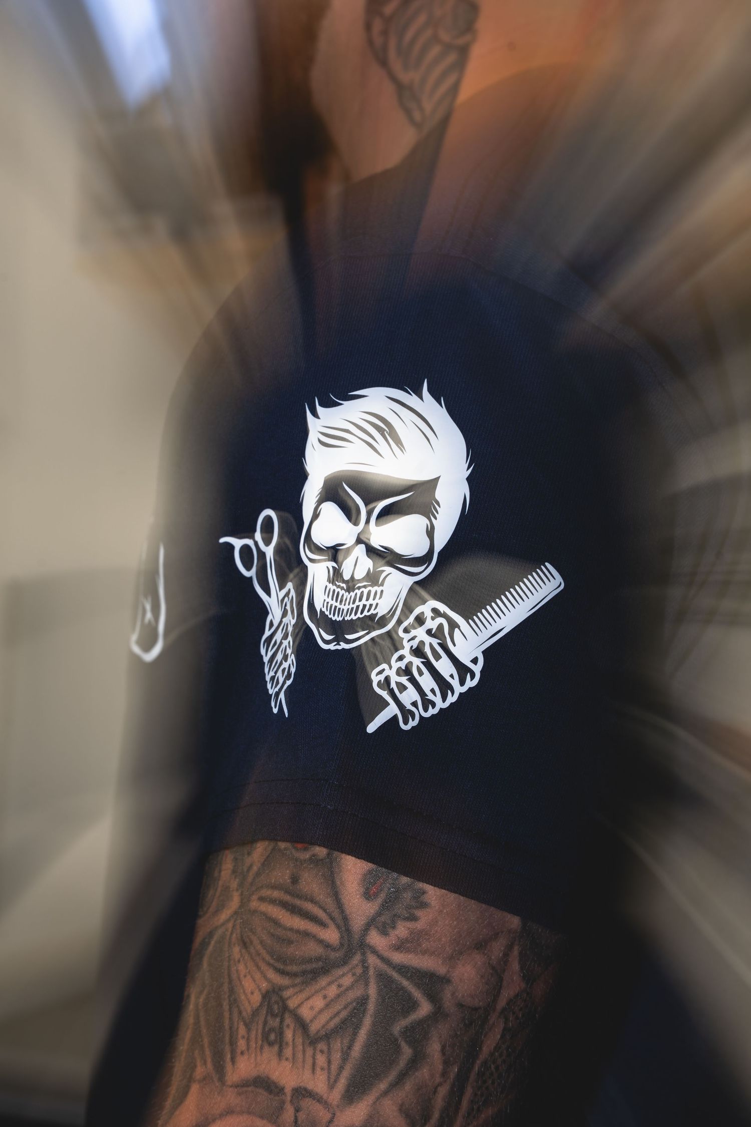 Black t-shirt with white skull barber logo holding scissors and comb.