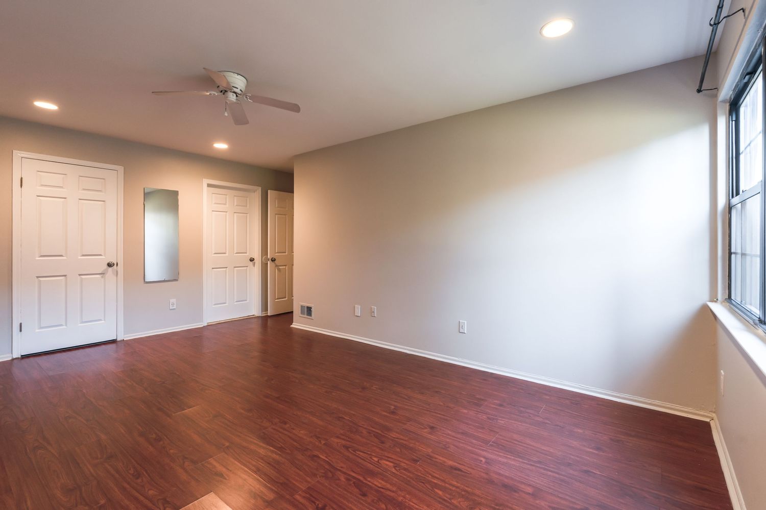 Modern apartment interior with recessed lighting and hardwood flooring showcasing an open layout living space.
