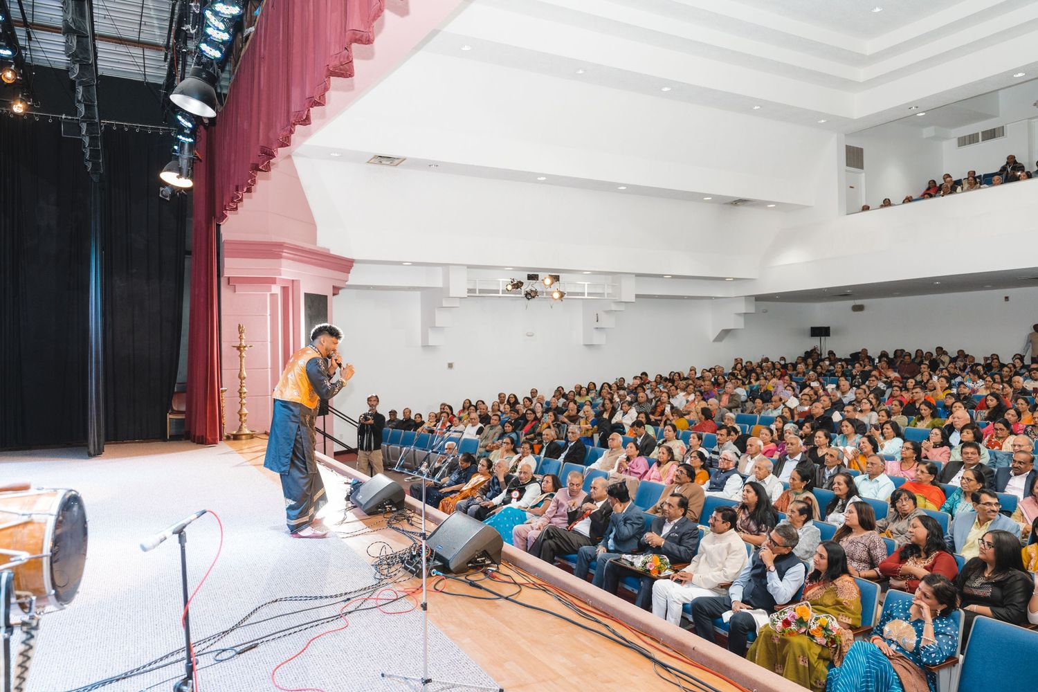 Large audience seated in rows fills a bright conference hall during a presentation event.