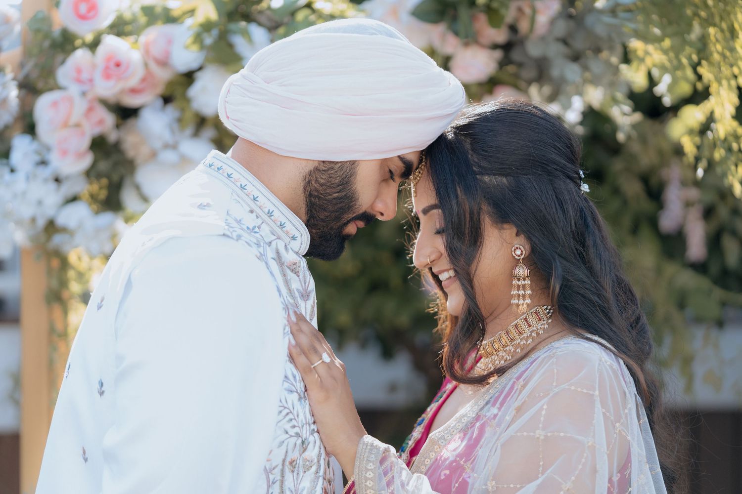 Couple in traditional attire sharing a romantic moment under blossoming trees.