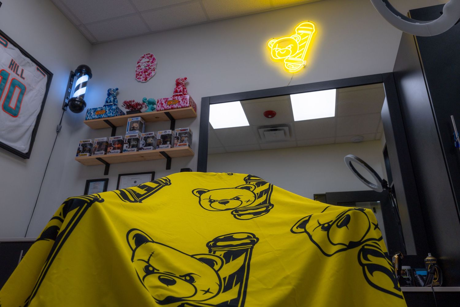 Yellow t-shirt merchandise displayed in a hair salon interior with bear logo branding.
