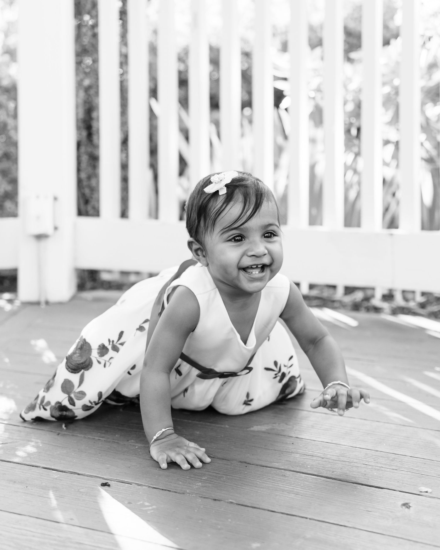 Black and white photos of a small child crawling on a wooden deck.