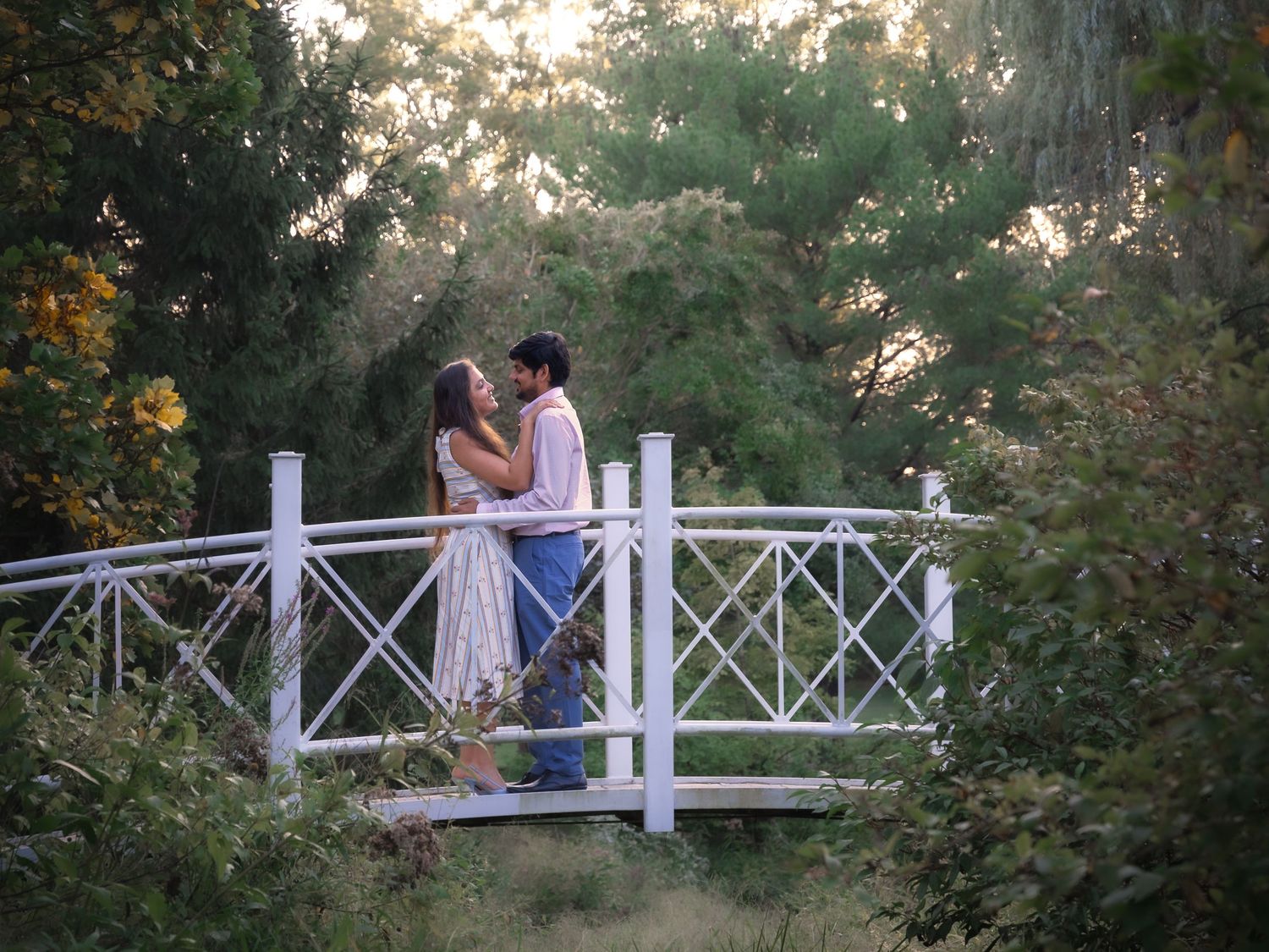 People sharing romantic moments on a white garden gazebo during golden hour.