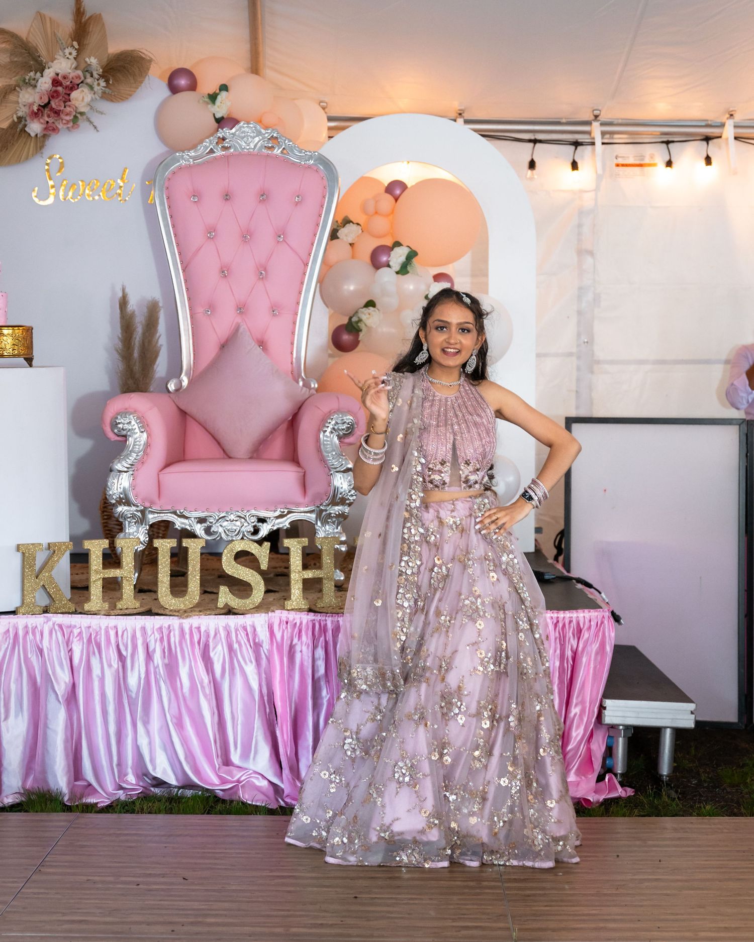 Sweet 16 party setup with pink throne chair, table skirt, and elegant decorations.