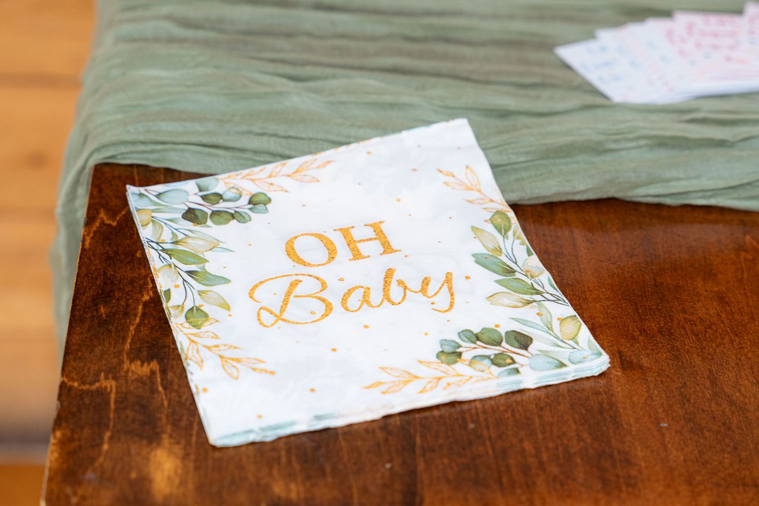Delicate floral baby shower cards and decorations laid out on a wooden table surface.
