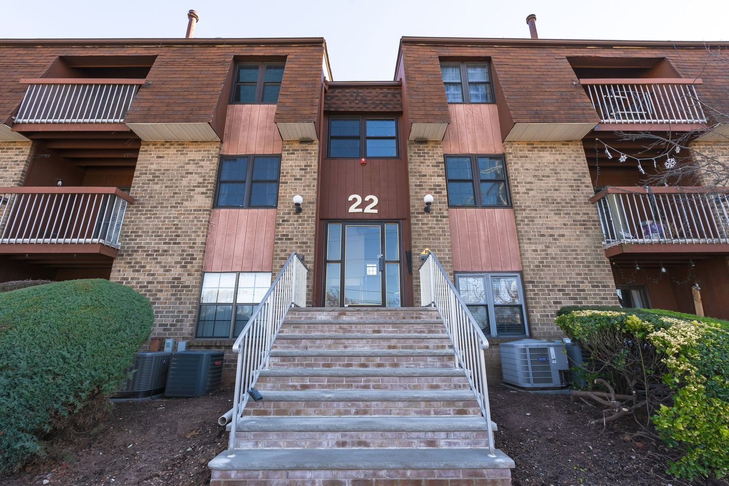 Exterior view of brick apartment building with concrete stairs and balconies showing different architectural perspectives.