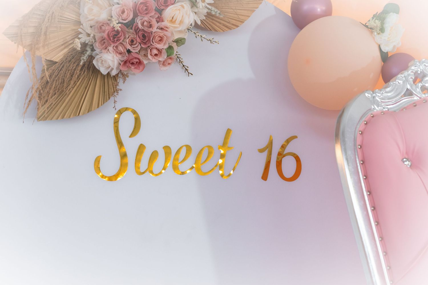 Elegant pink and peach toned party decorations with floral accents and balloons.
