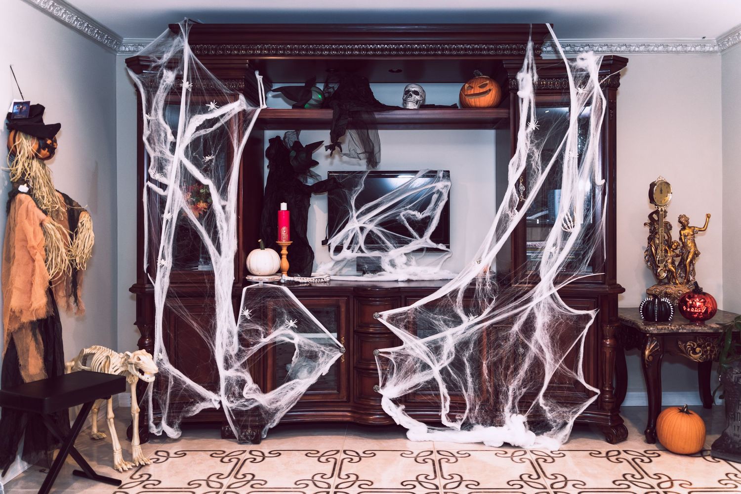A Halloween display features white spooky tree branches and orange pumpkins decorating a modern interior space.