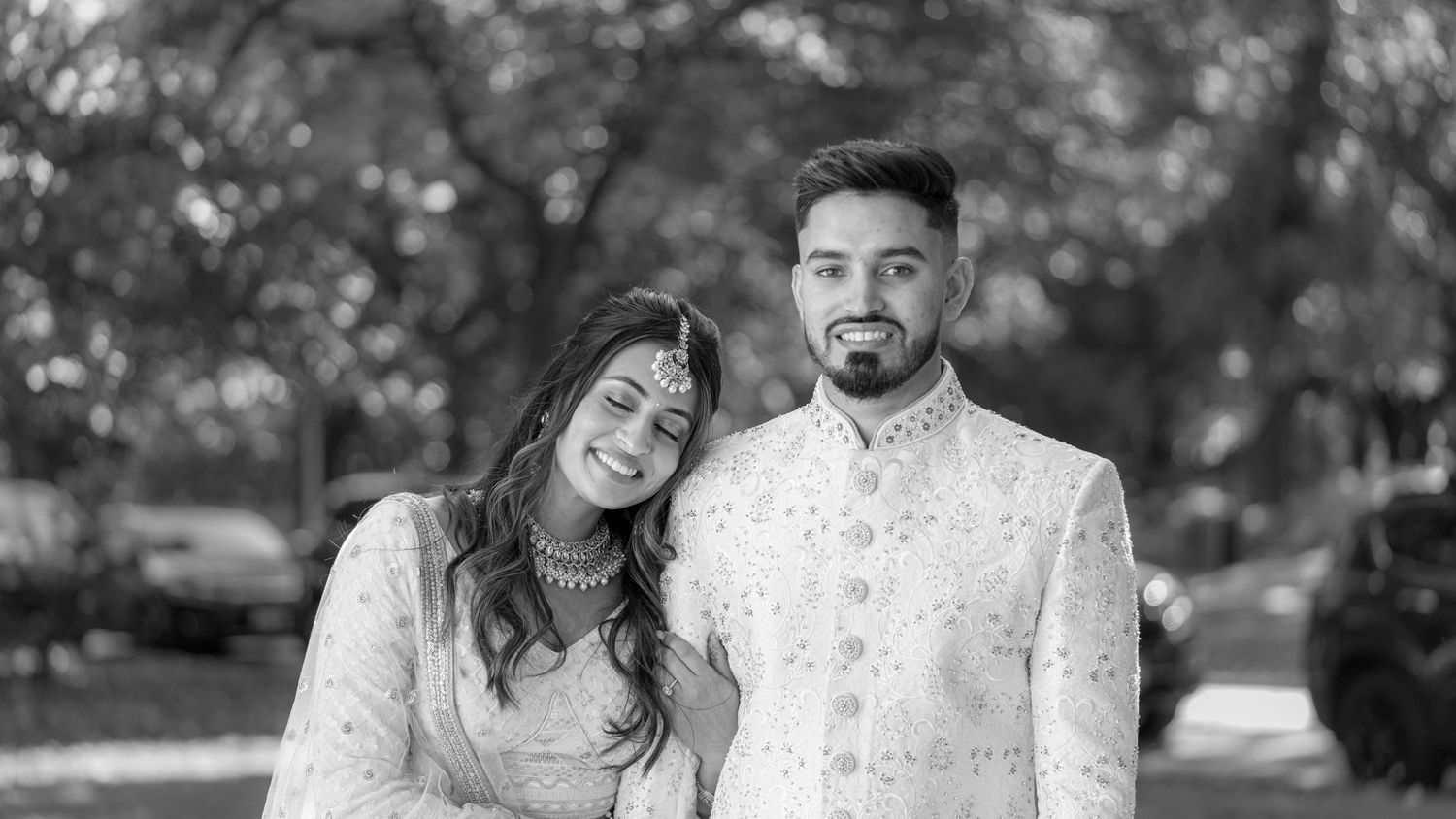 Black and white portrait of a couple in formal attire outdoors.