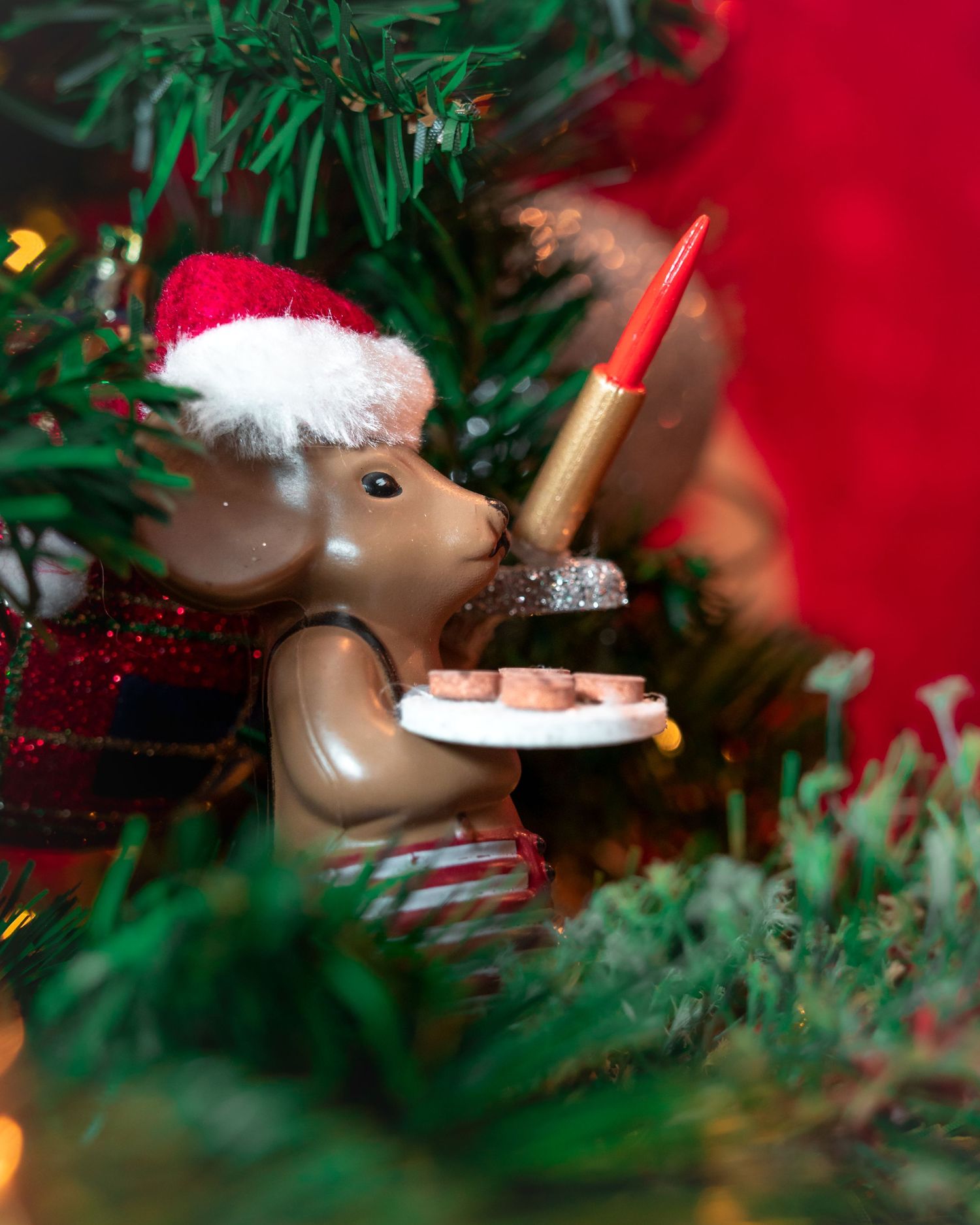 A close-up sequence of a reindeer Christmas ornament with a pipe nestled among green pine branches.