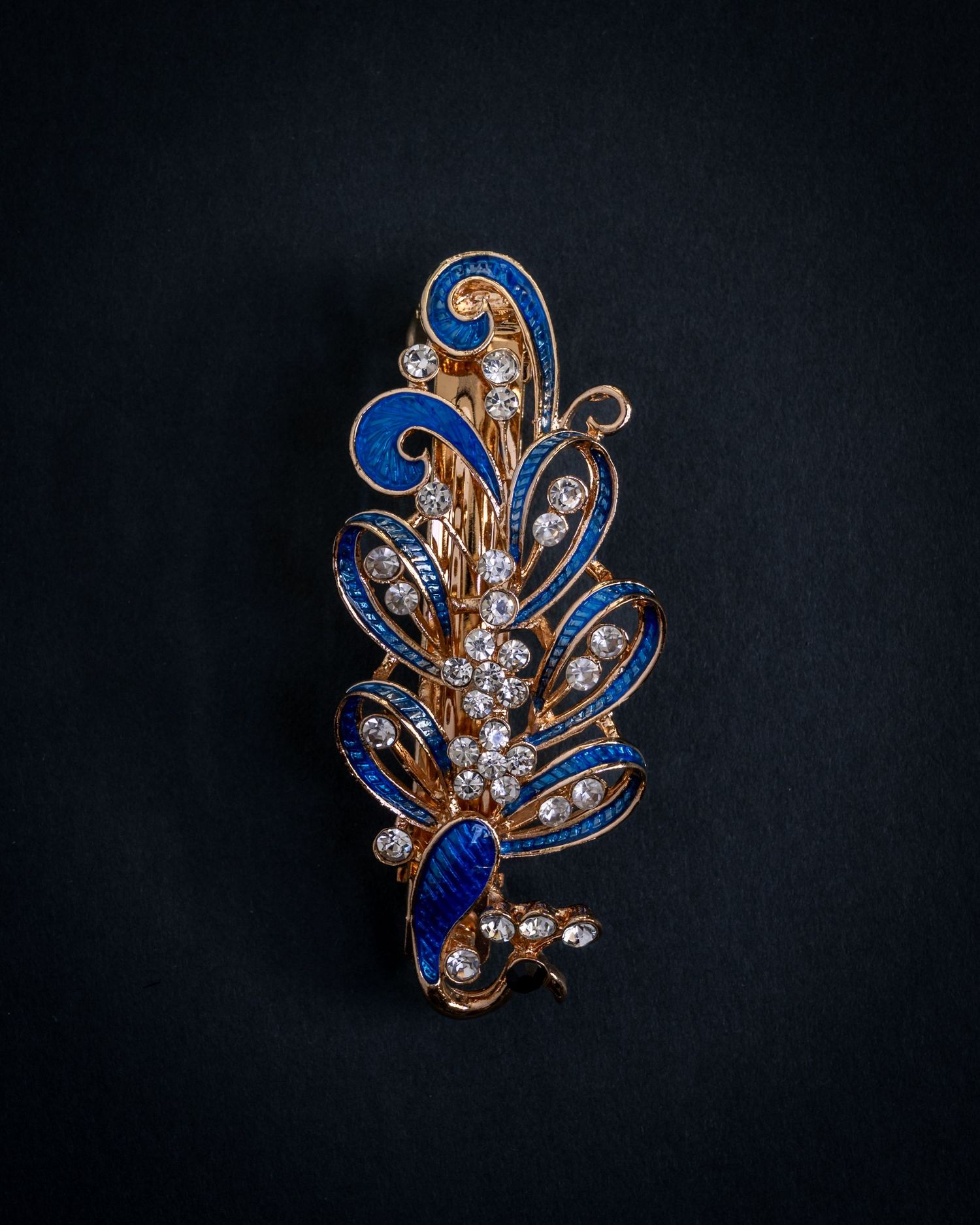 Vintage gold brooch with sapphire blue enamel and crystal accents photographed from three different angles on dark background.