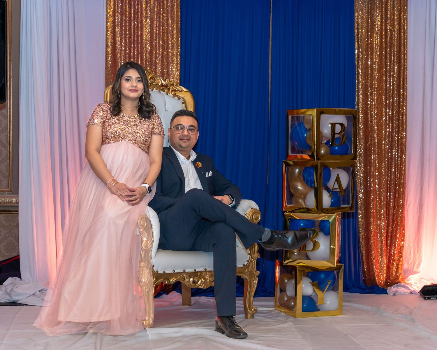 Elegant event setup with royal blue curtains and gold sequin backdrop.