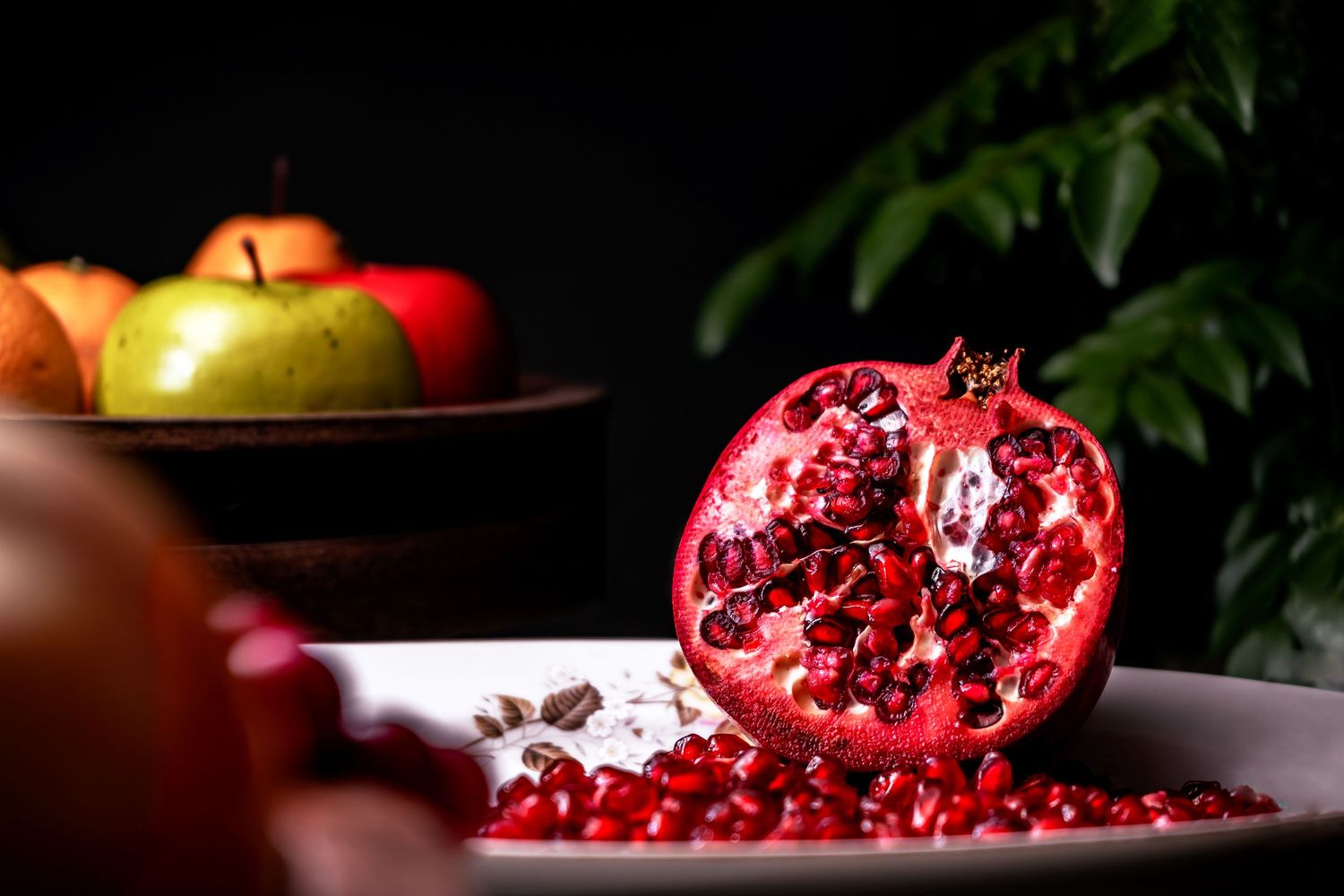 Fresh pomegranate cut open revealing bright red seeds on a dark background.