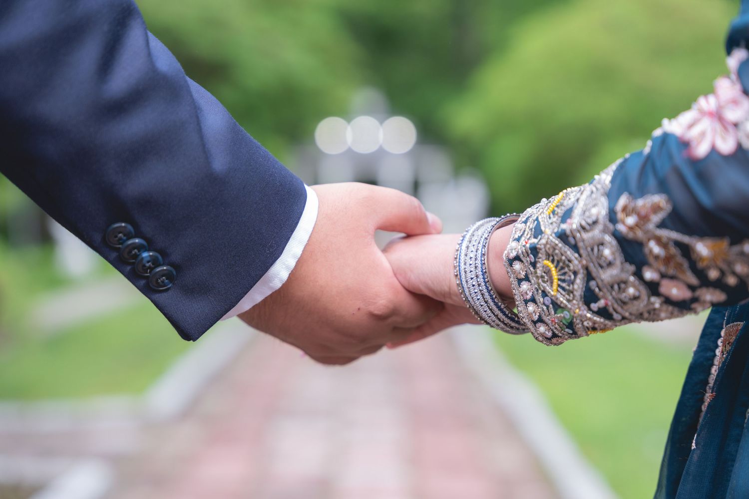 Close-up of hands holding during an outdoor garden wedding ceremony.