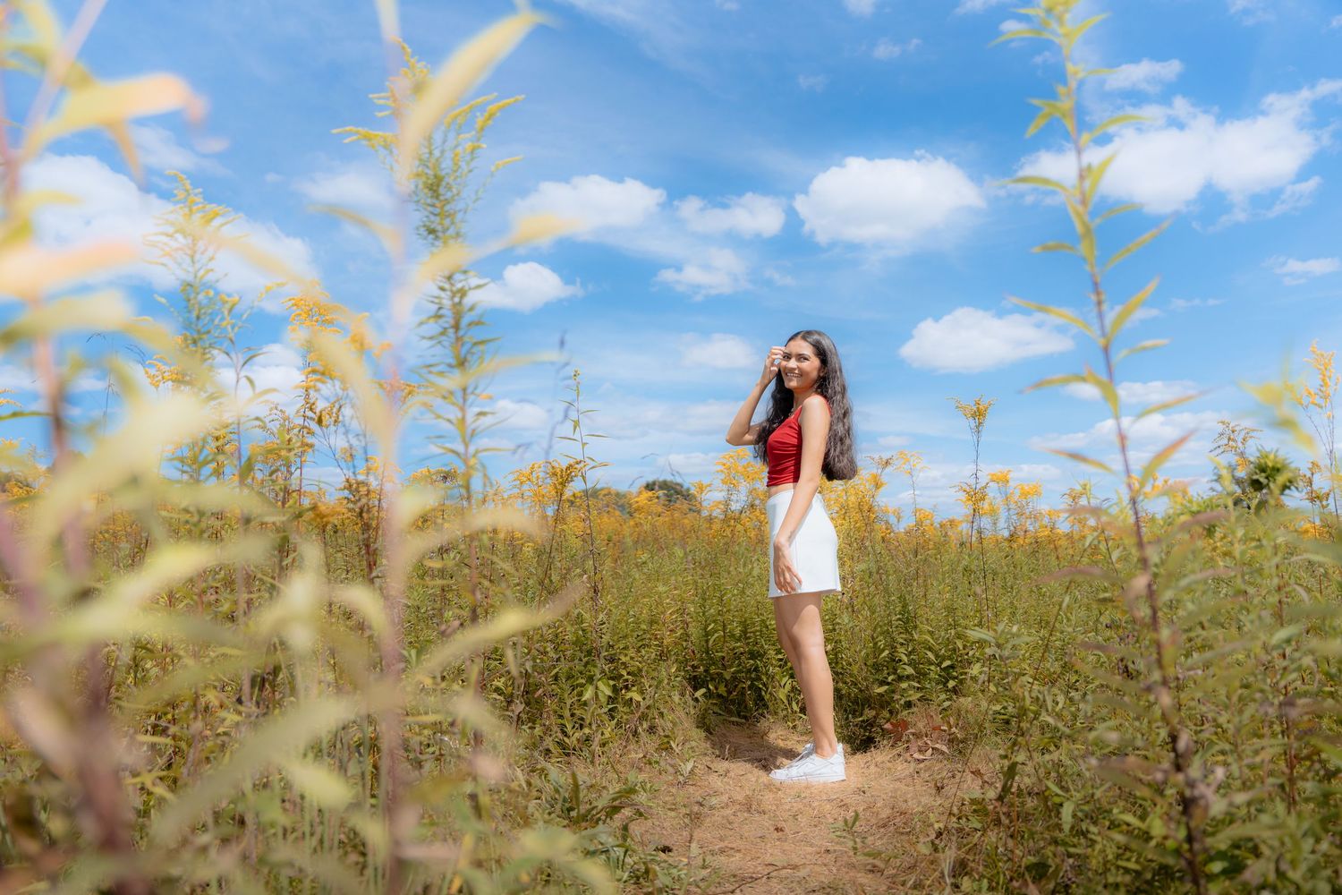 Someone walking through a beautiful yellow wildflower field on a sunny summer day.
