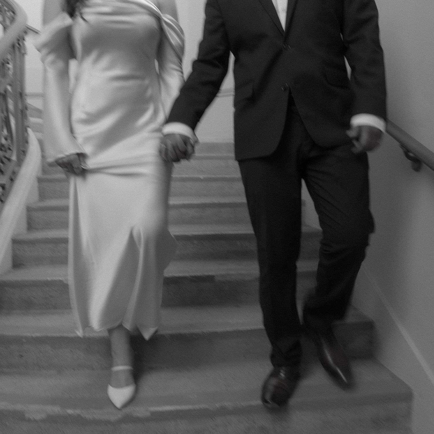 Couple descending stairs in formal attire shown in black and white.