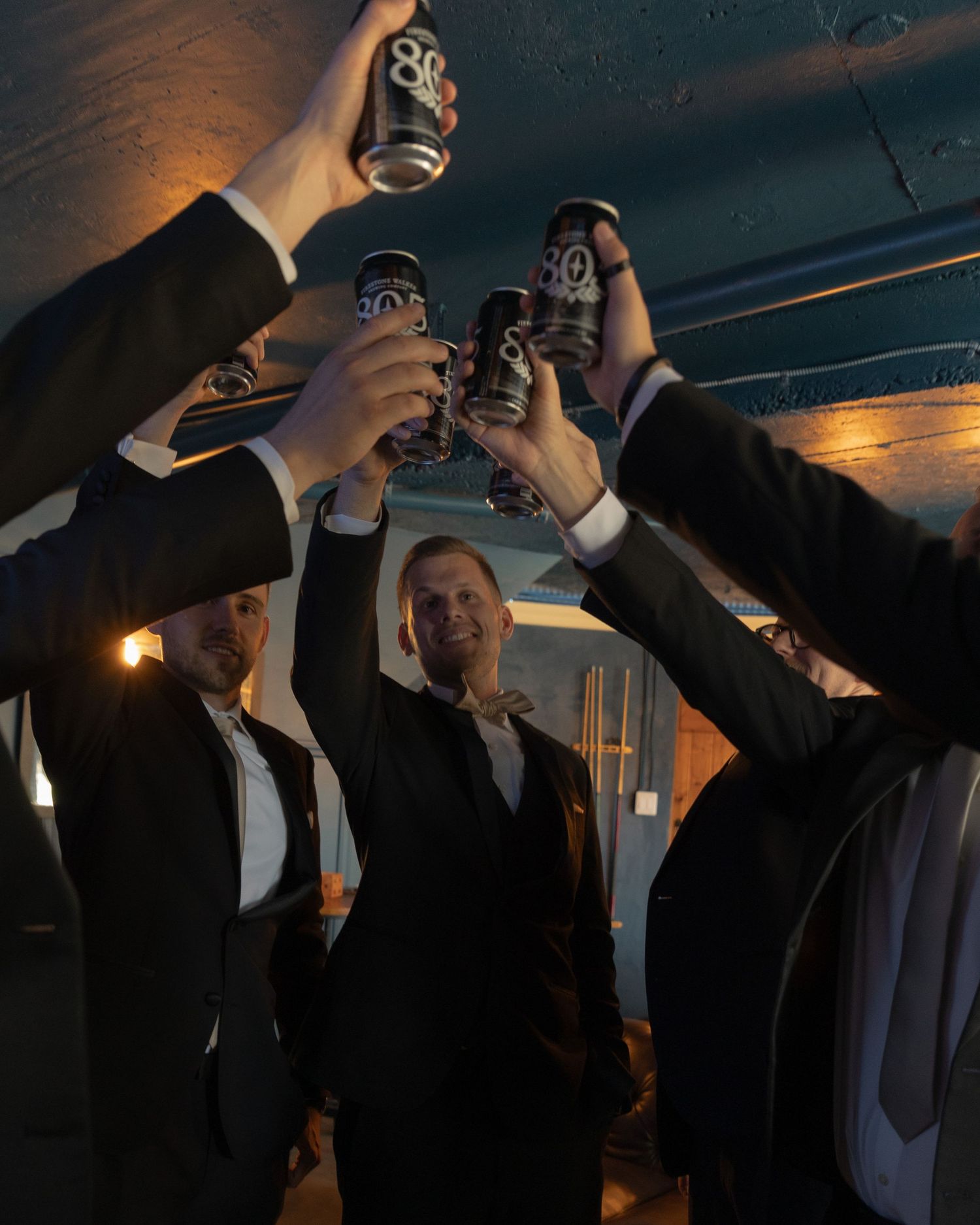 Group taking celebratory shots at sunset during wedding reception.
