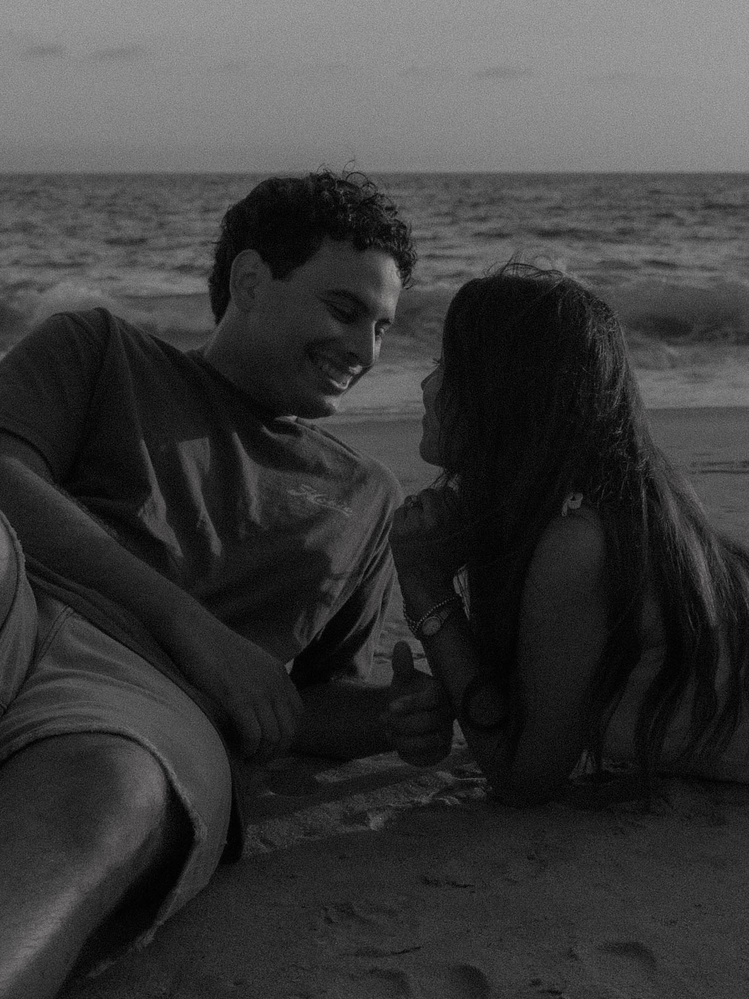 A romantic black and white photo sequence shows a couple embracing and kissing on a beach by the ocean.