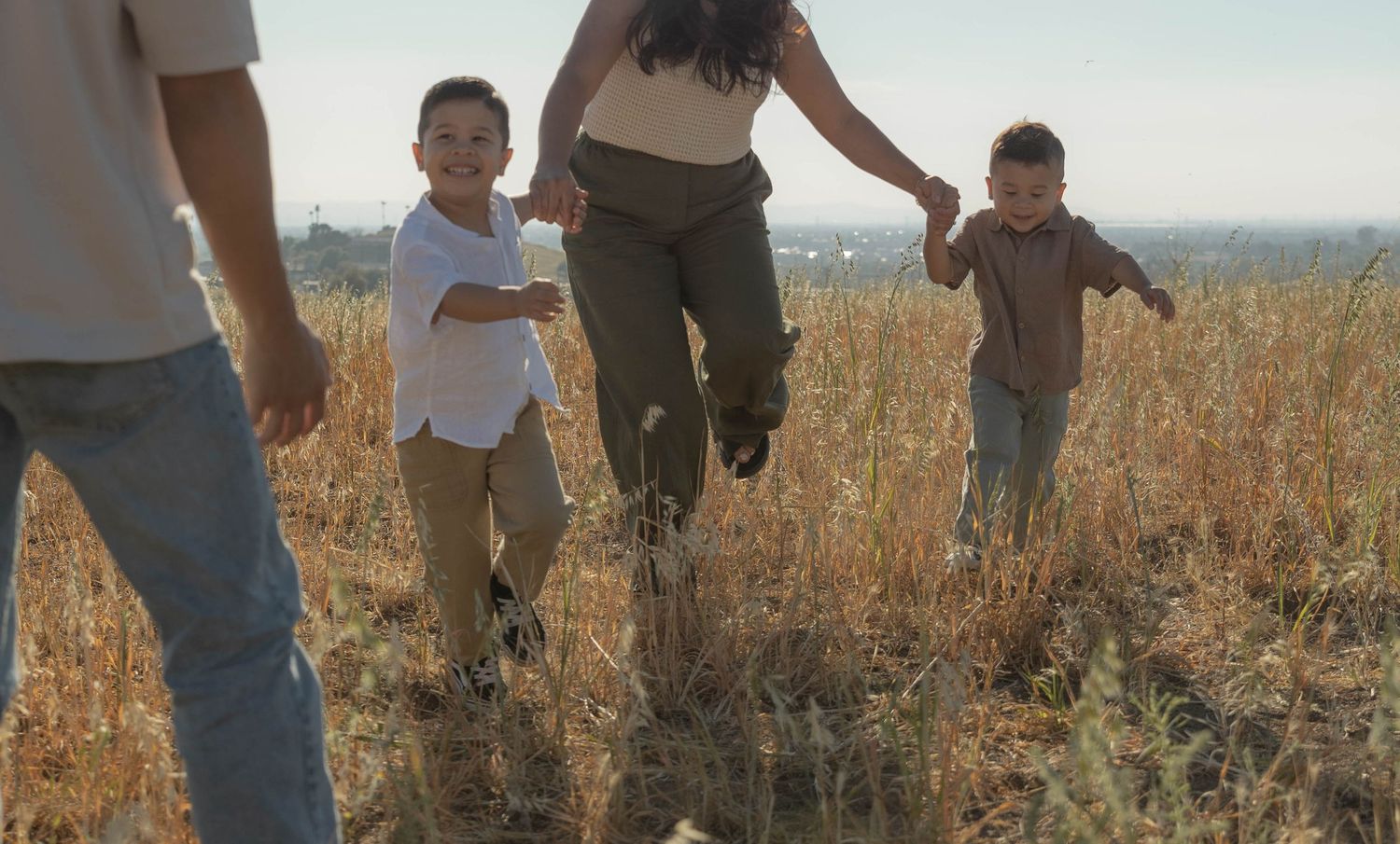 People walking through a sun-drenched field of tall grass.