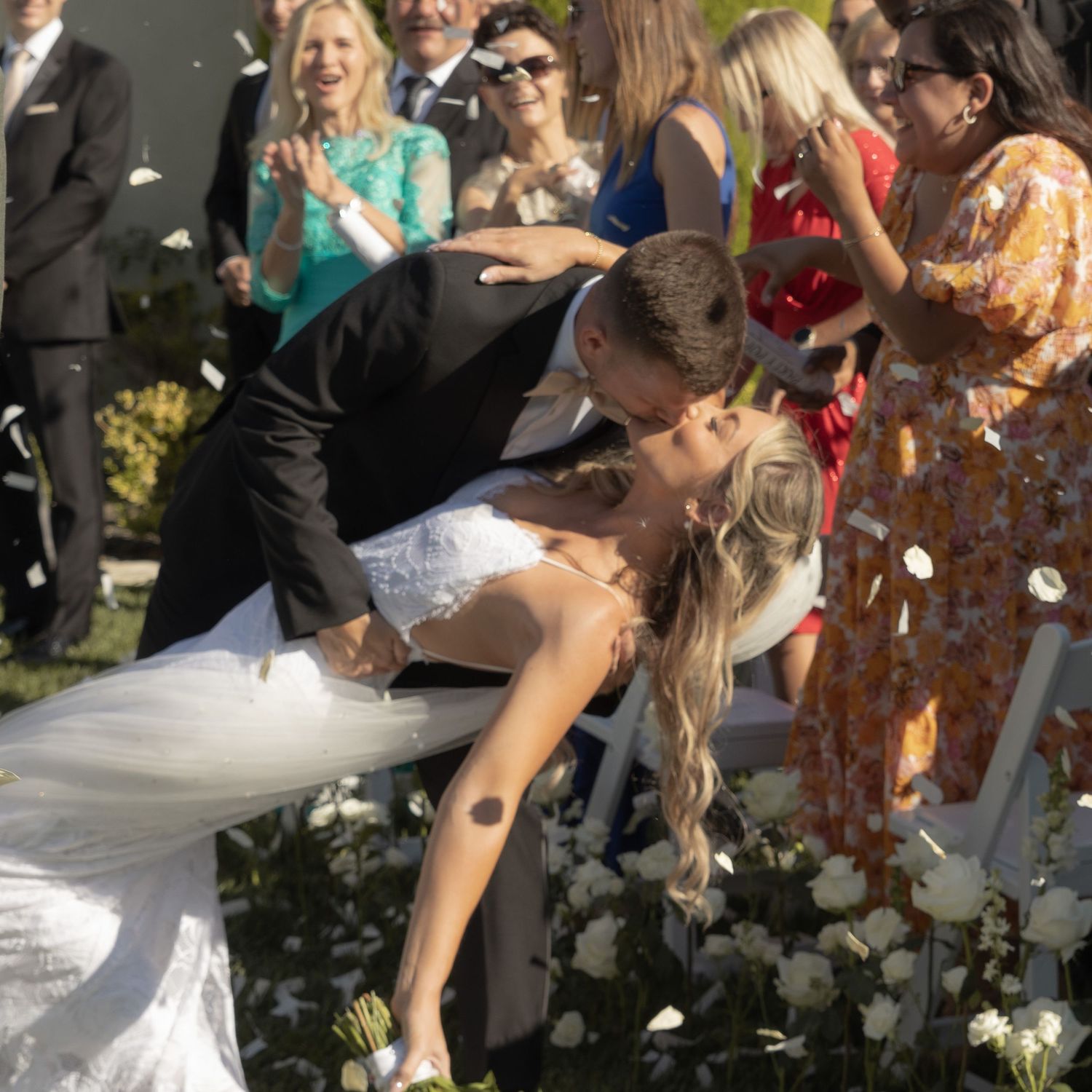 Wedding guests throwing white petals during an outdoor celebration.