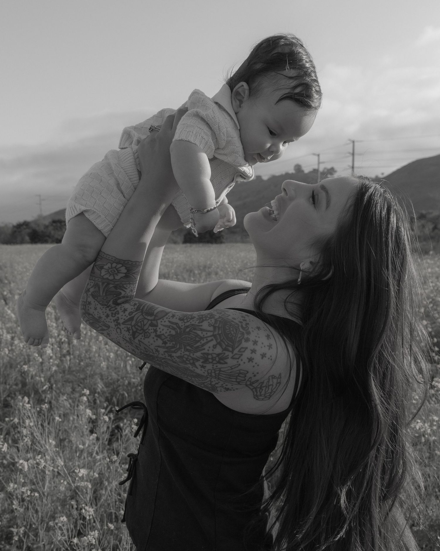 A black and white photo captures a playful moment between two people in a flower field.