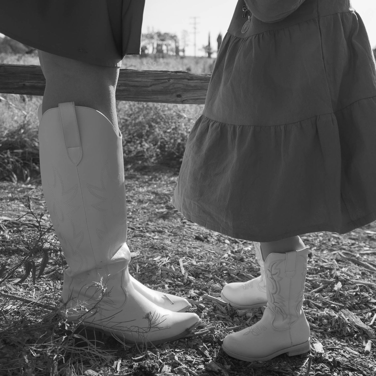 Close-up of boots and dress hems in black and white photography.