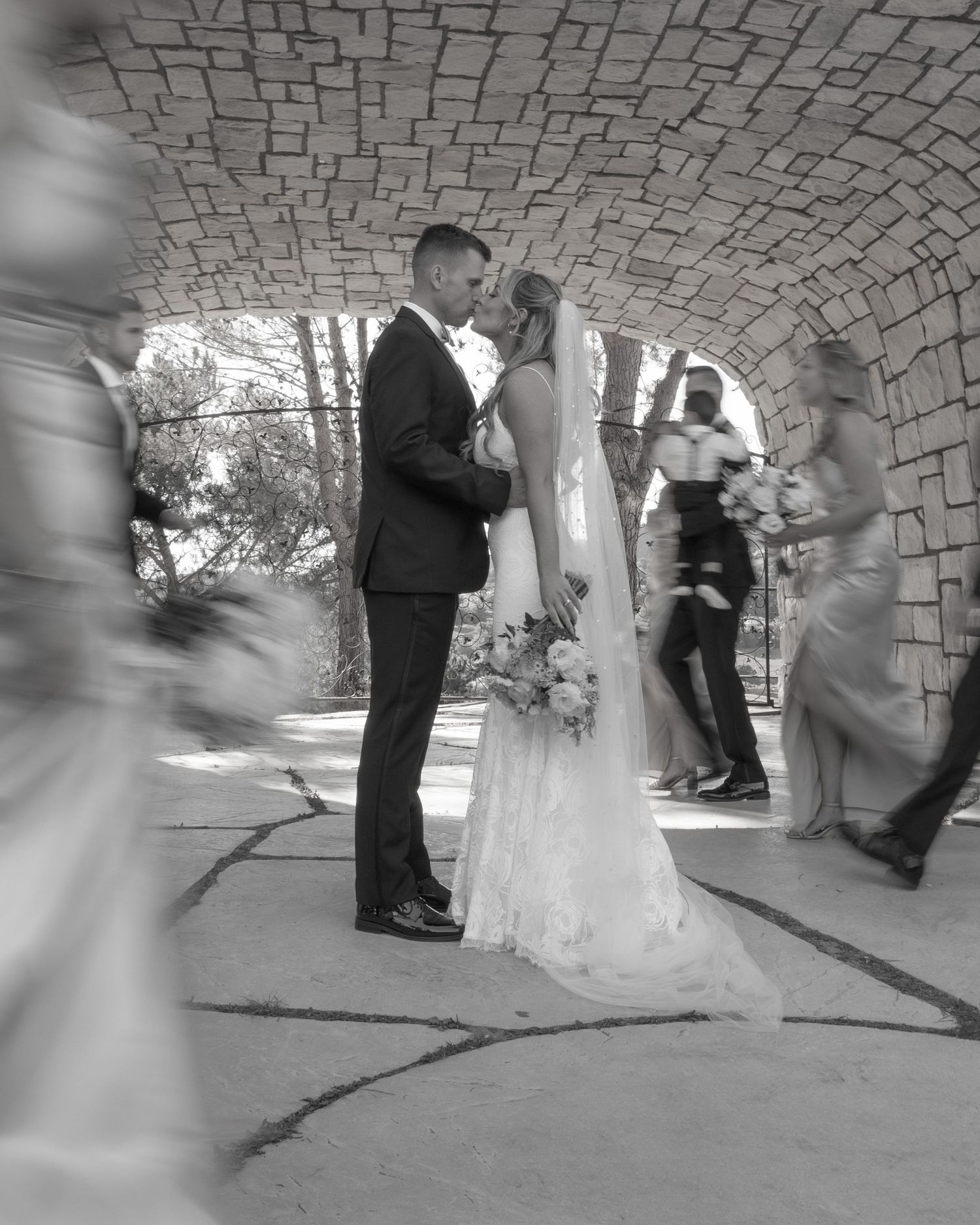 Black and white wedding ceremony photos taken under a stone archway.