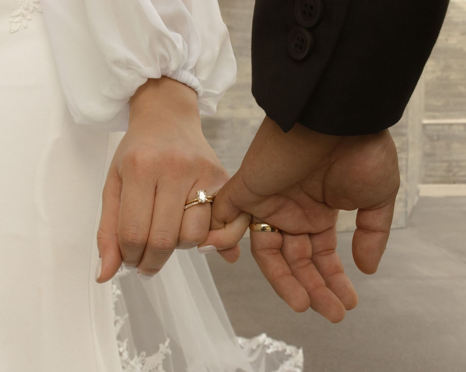 Close-up of newlyweds holding hands displaying wedding rings after marriage ceremony.