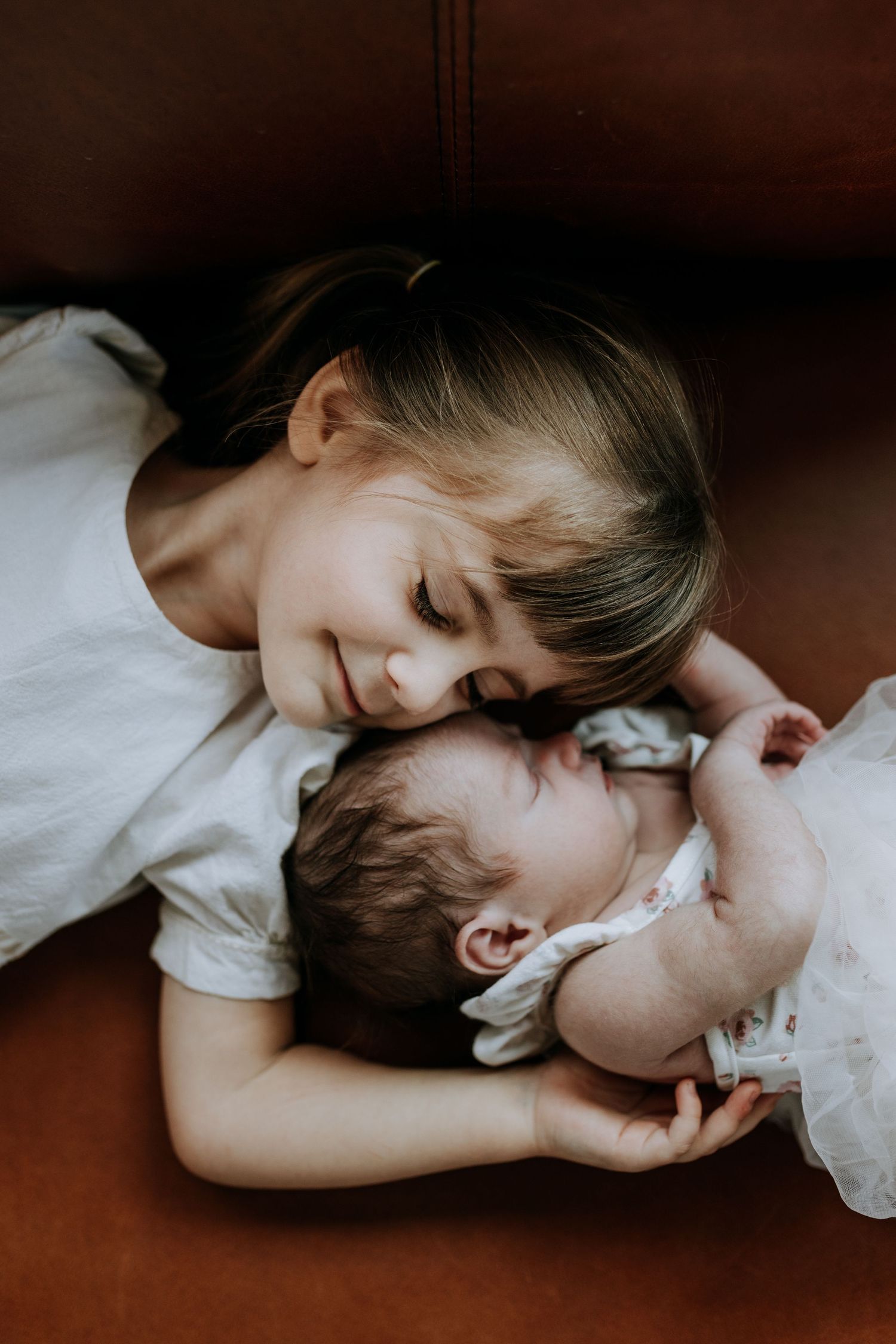 A tender close-up moment is captured in a series showing a sweet interaction between parent and child on white bedding.