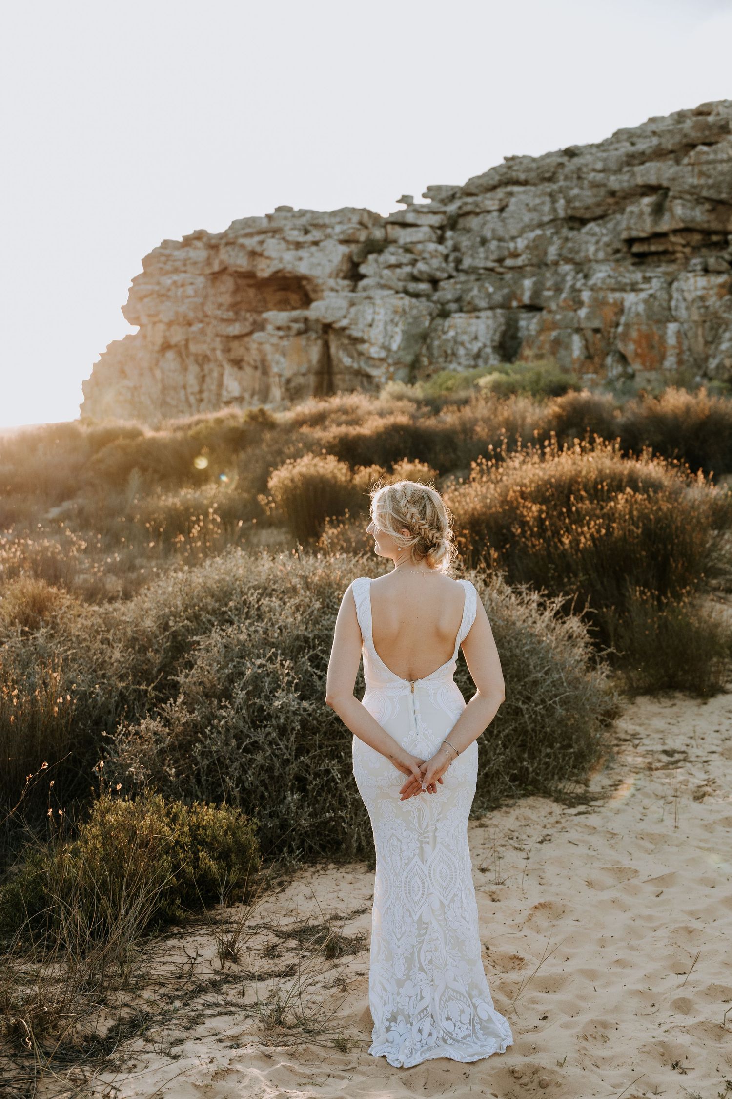 White lace dress photographed against rocky desert landscape at sunset.