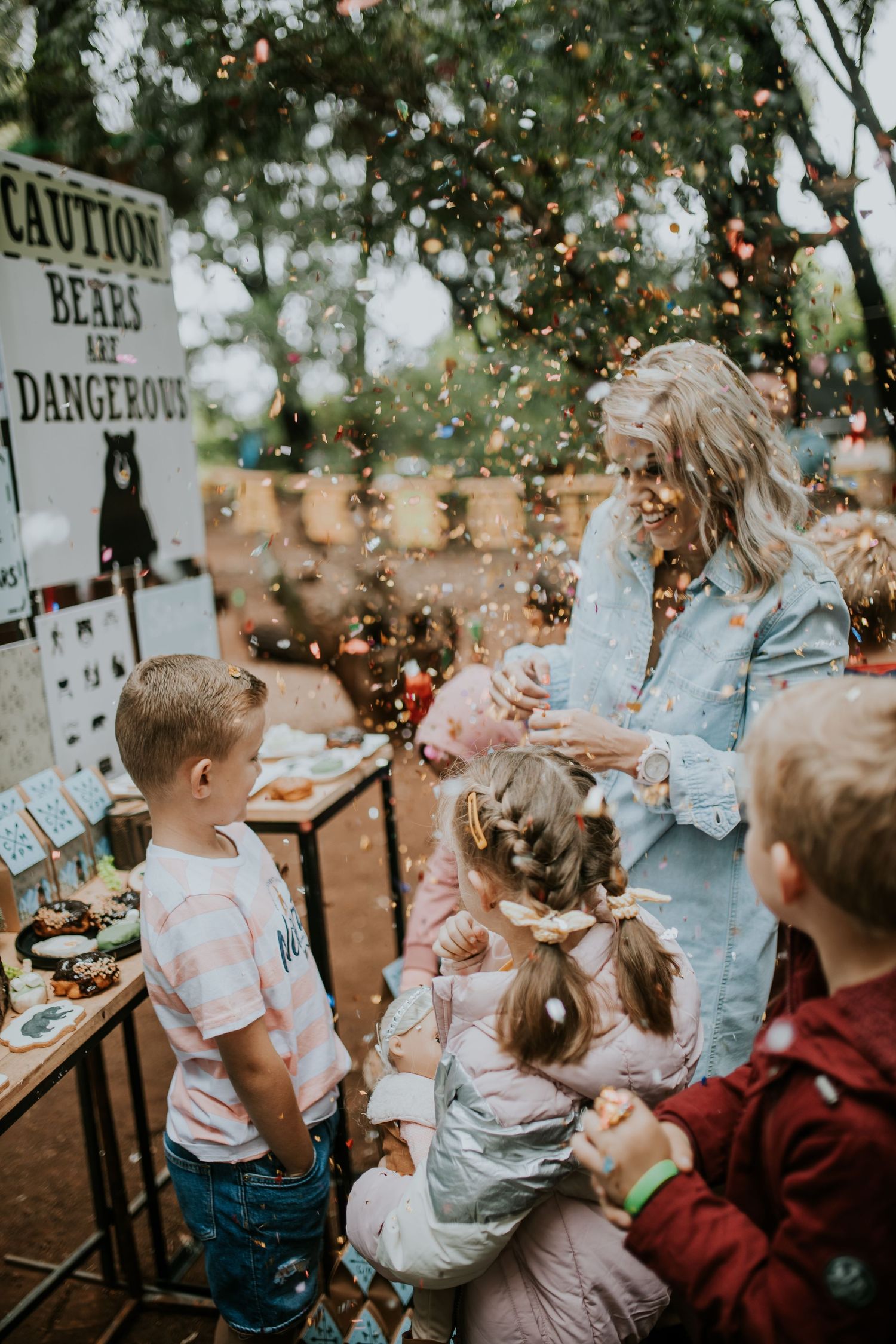 Children playing and throwing confetti during an outdoor birthday party celebration in natural lighting.