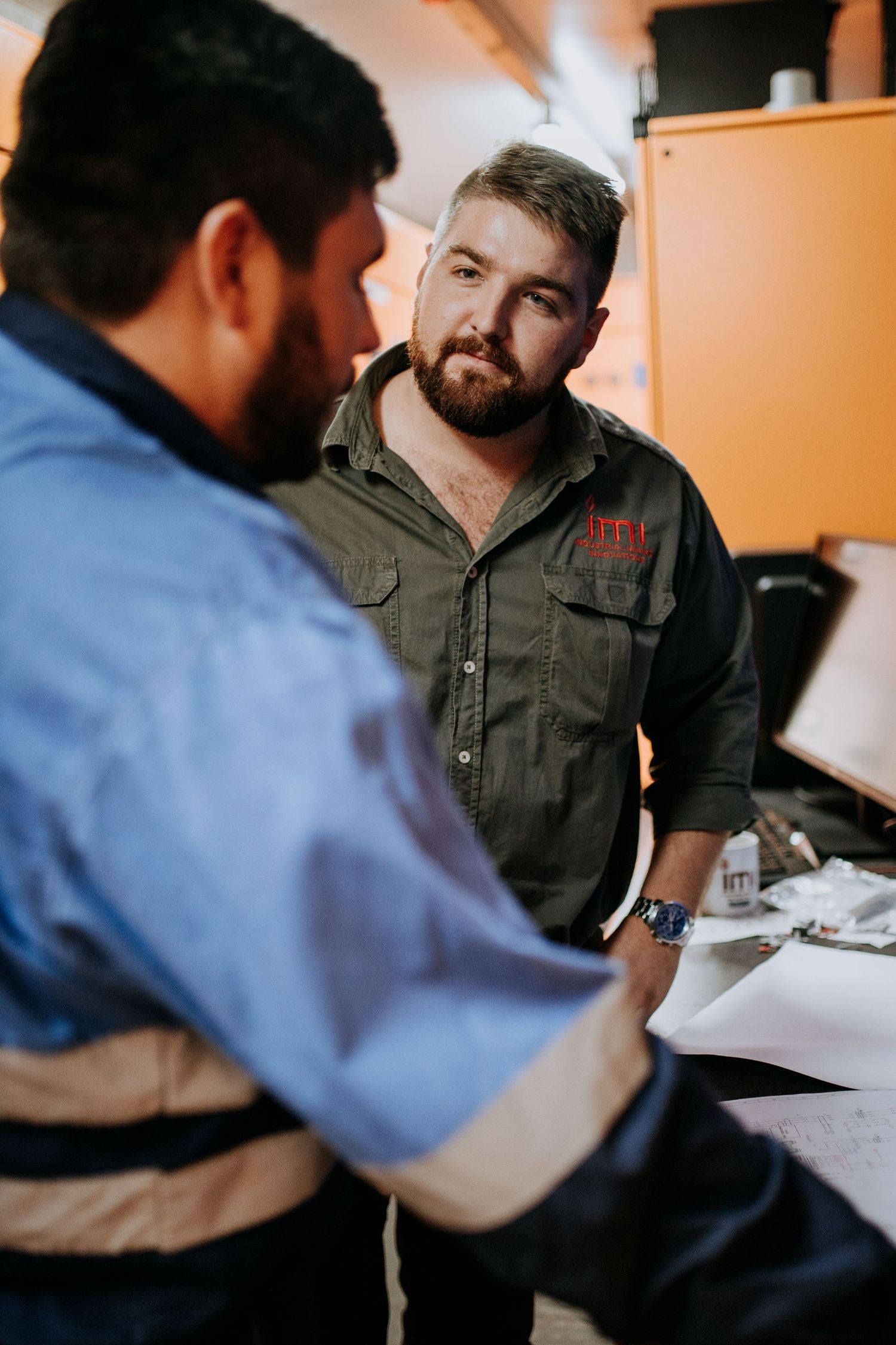Two people meeting and reviewing documents together in an office setting.