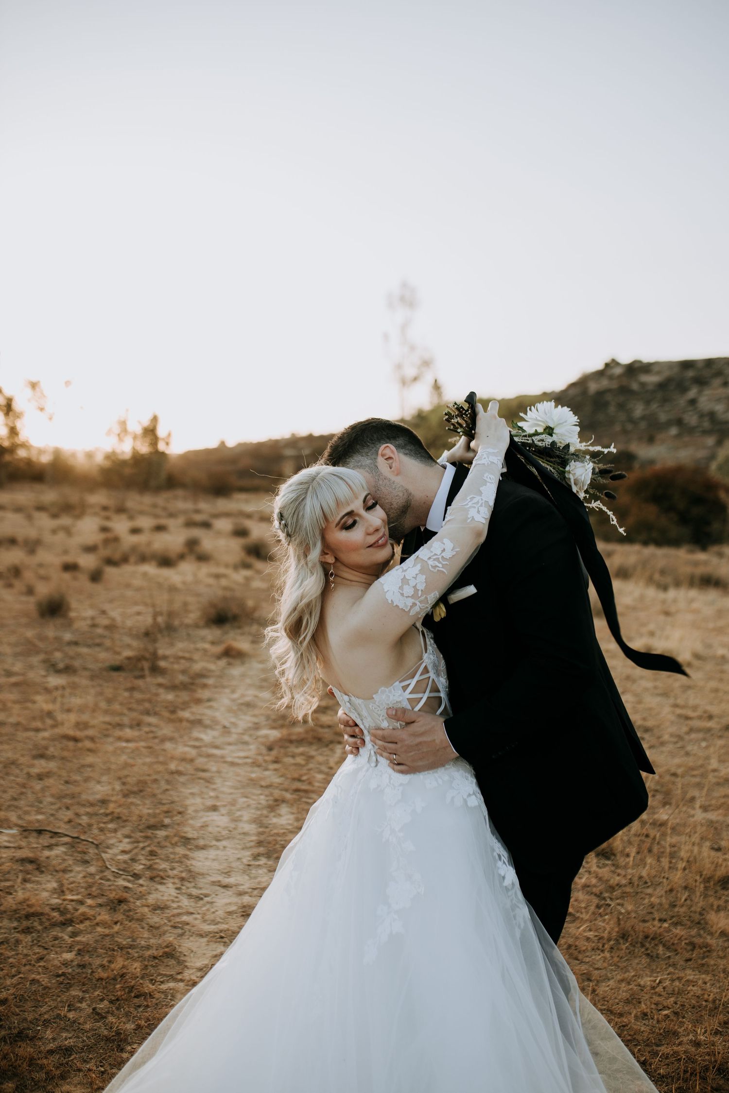 A romantic wedding couple embraces and dances in a desert landscape at sunset, captured in three sequential photos.