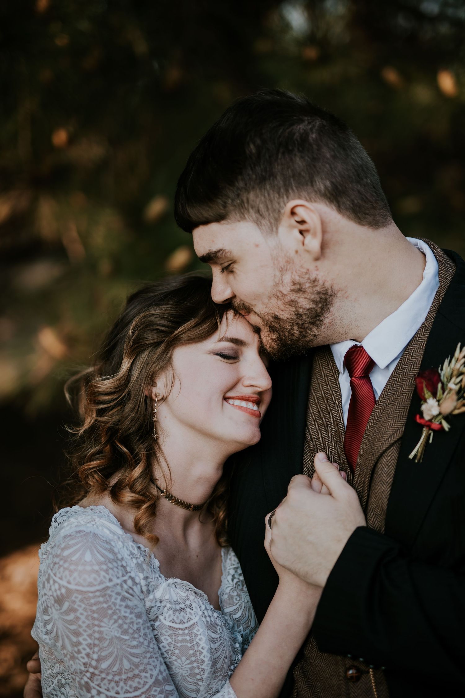 Romantic wedding couple shares intimate moments together in autumn woodland setting.
