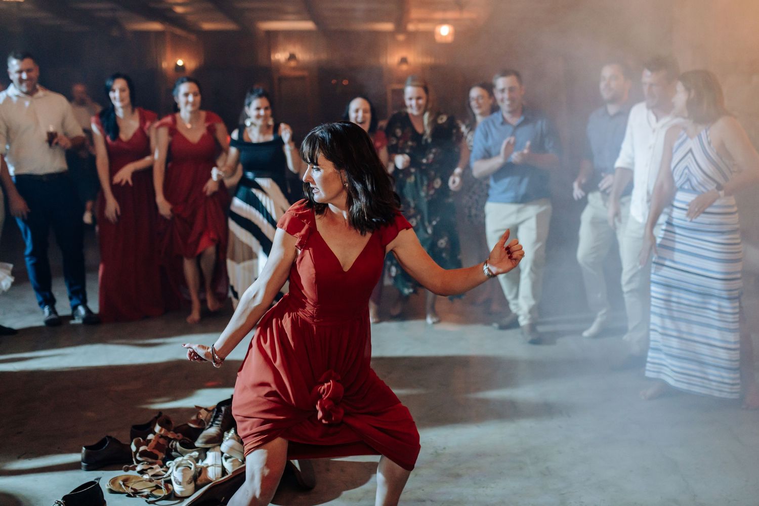 Five couples in formal attire glide across a misty dance floor at an elegant social event.