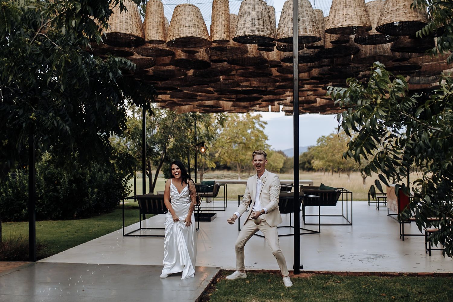A rustic outdoor wedding venue features a wooden pergola and elegant seating arrangements during a beautiful ceremony setup.