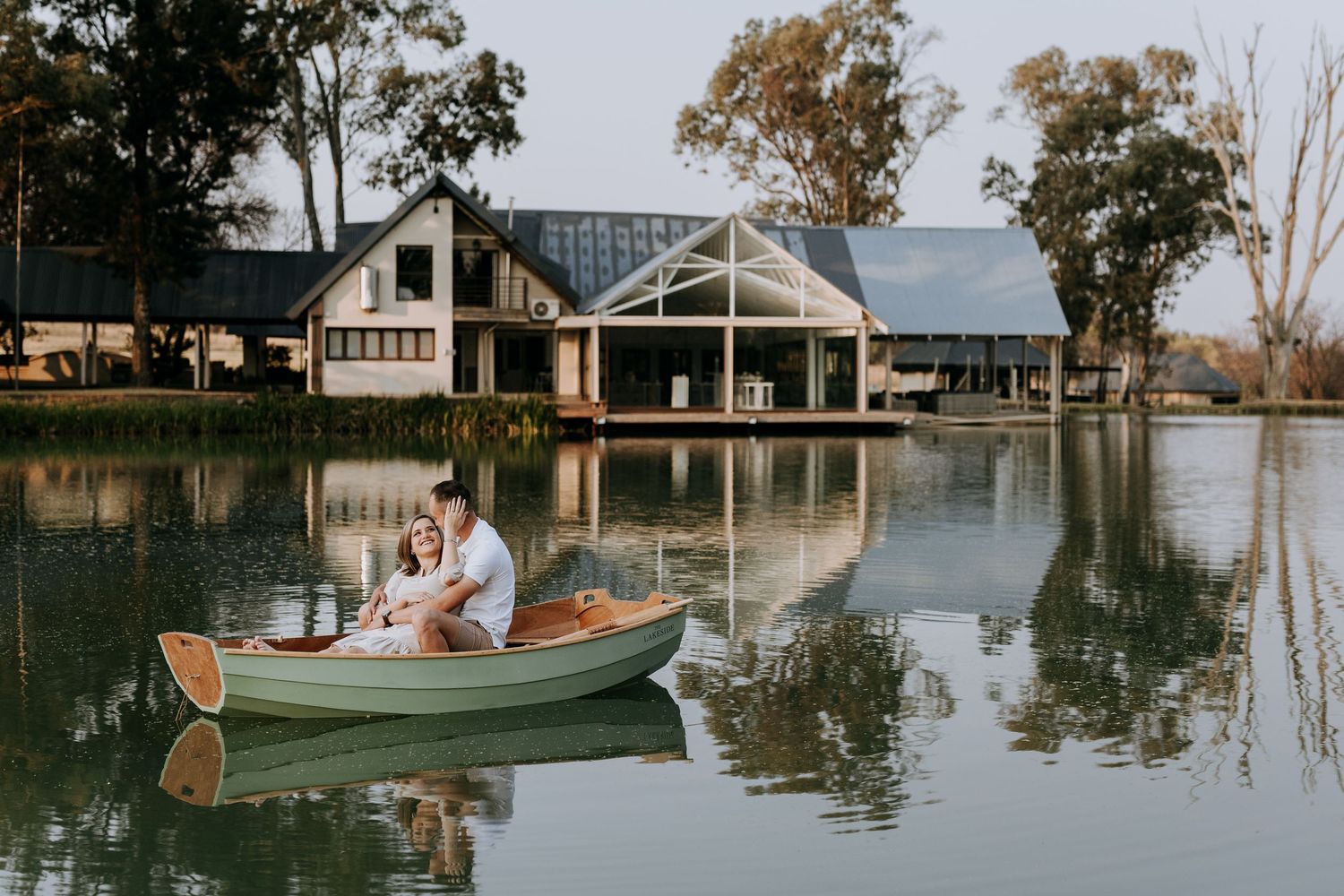 A romantic boat ride through calm waters with reflection of trees and buildings at a lakeside resort destination.